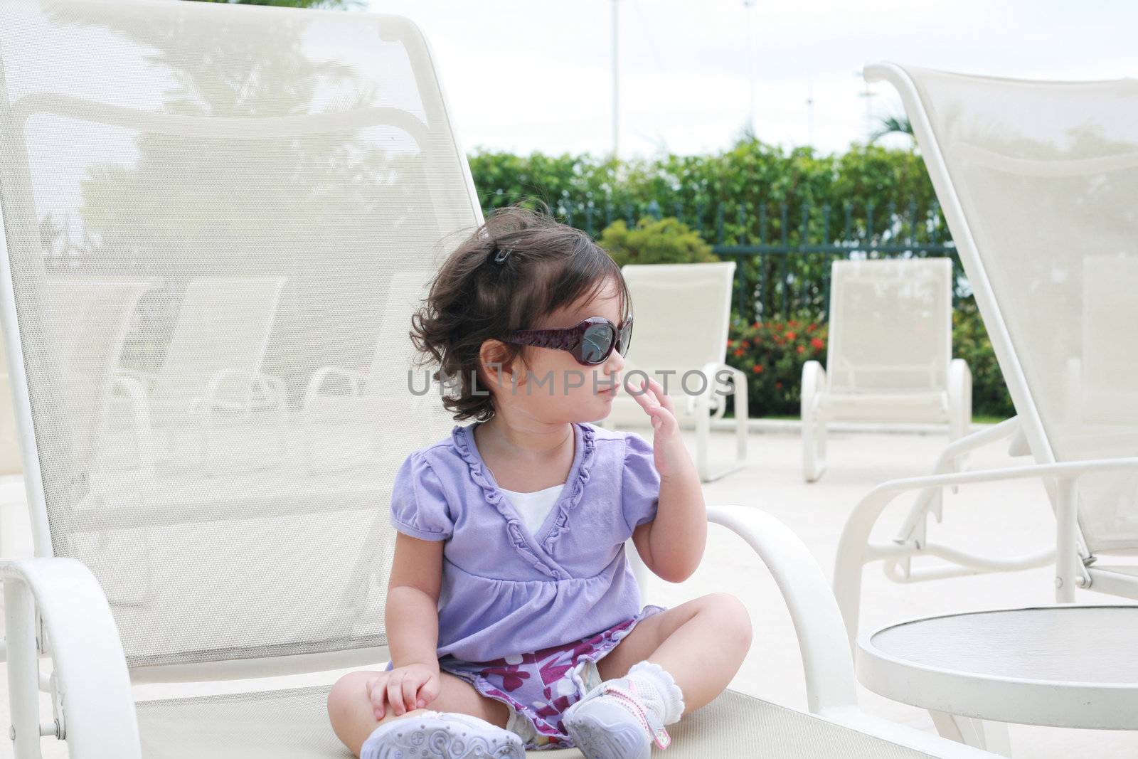 adorable young baby girl wearing sunglasses in flirting position