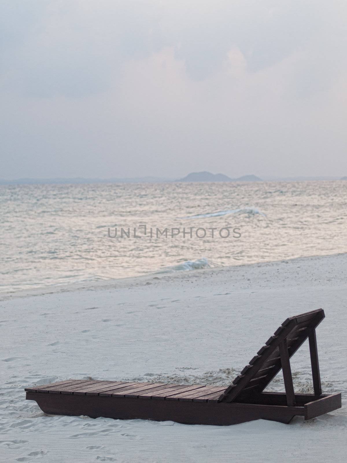 Empty  wooden chair on the beach at  dawn  on an tropical island