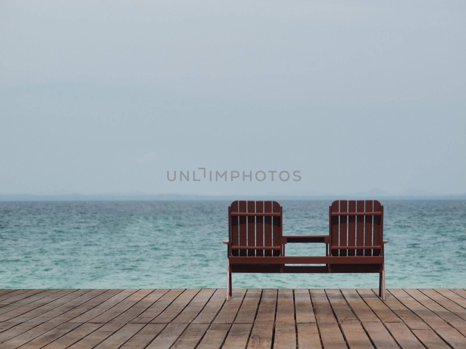 Two empty chair at a resort facing the south China sea in Pulau Besar Malaysia with a boat in the background