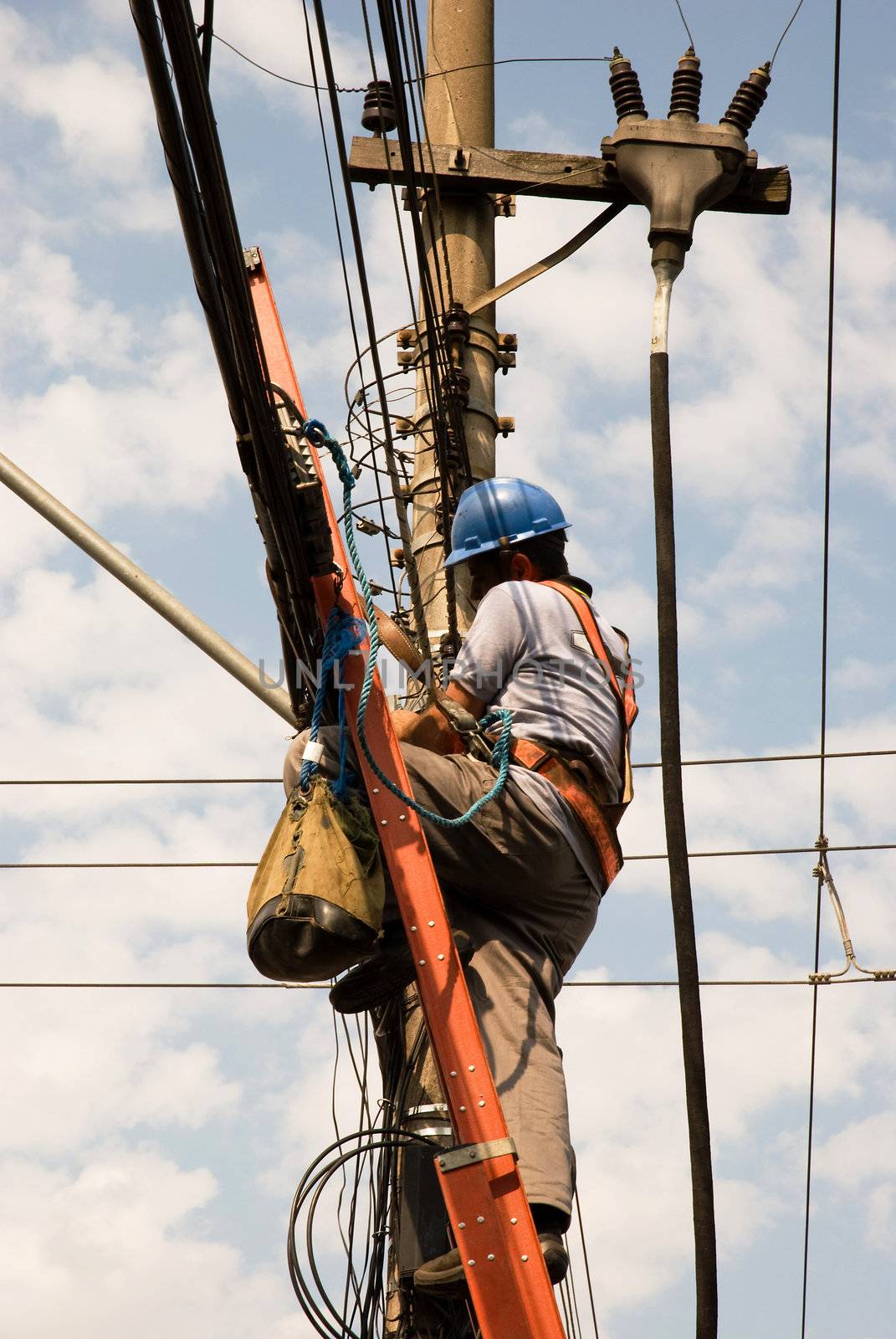 Unrecognisable of utility worker (from the side) with electrical cables in the background.