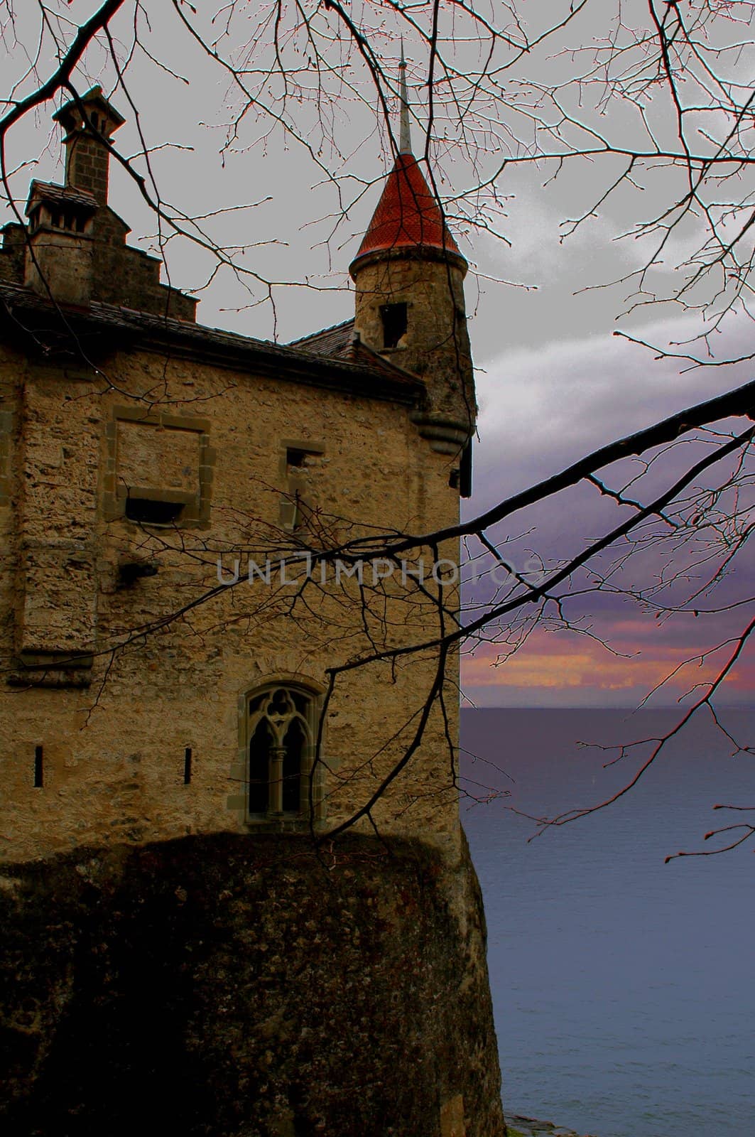 Image of partial castle on left with yelllow sky, clouds, mountains and Lake Geneva.