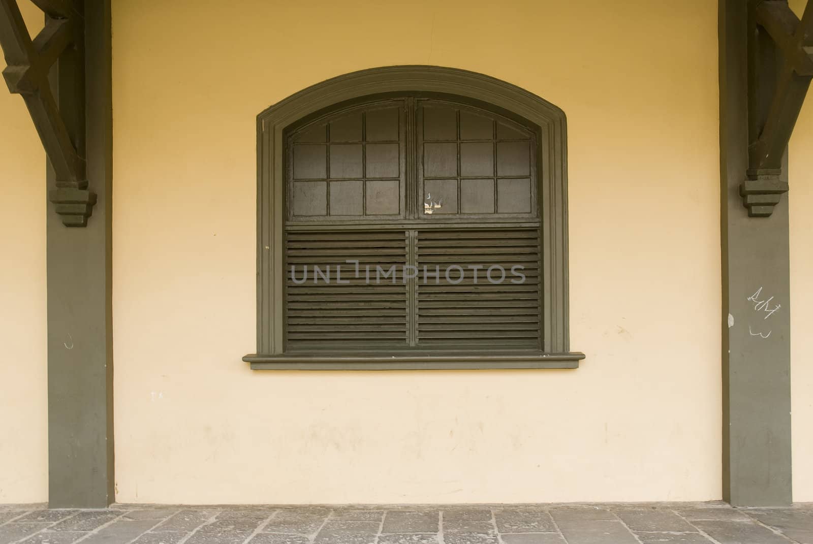 Front shot of a rustic brown wooden window, with cream coloured wall.