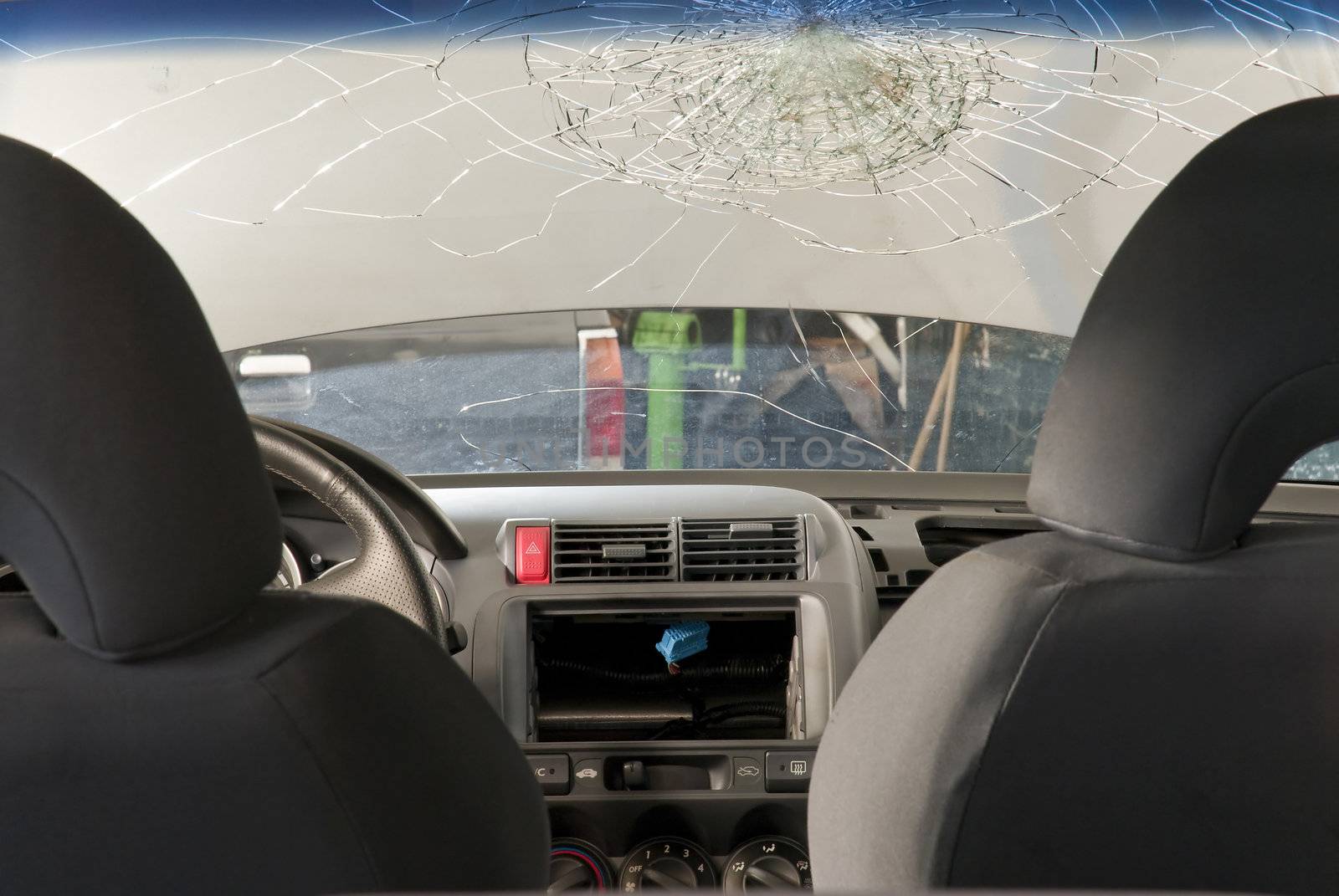 Detail shot of a shattered car windshield in a repair shop. Shot from inside the car.