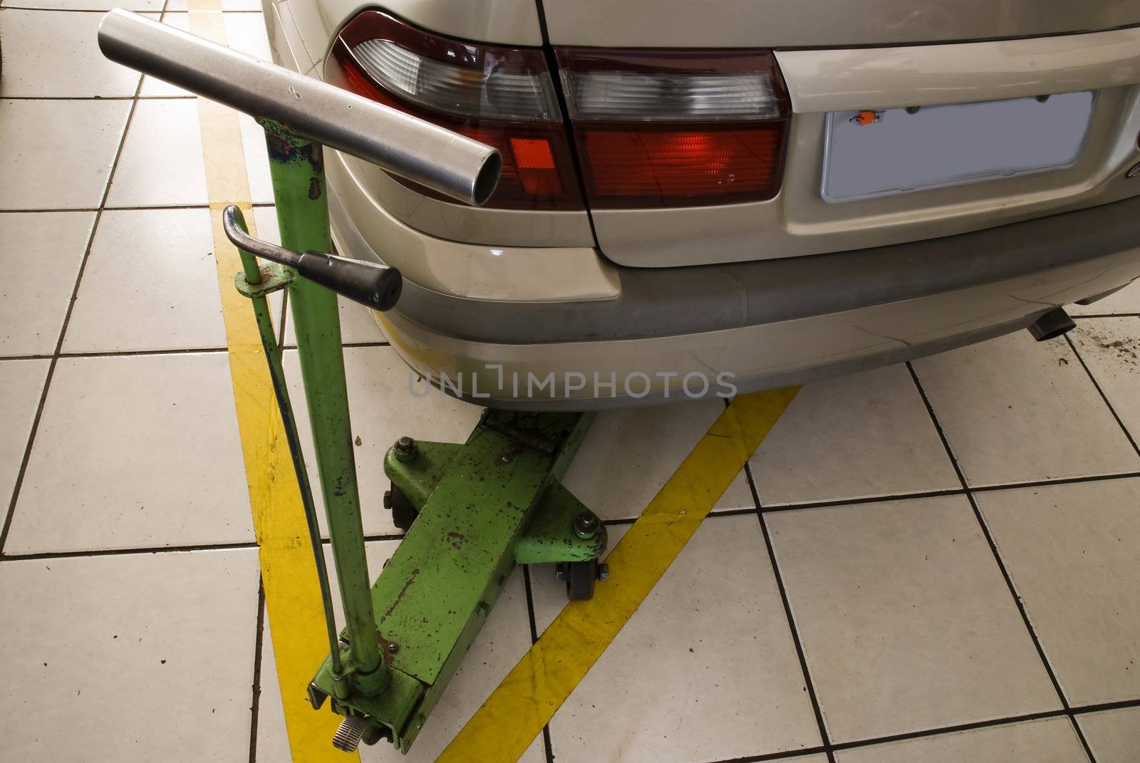 Detail of rear of a beige car with underhoist. Shot from above