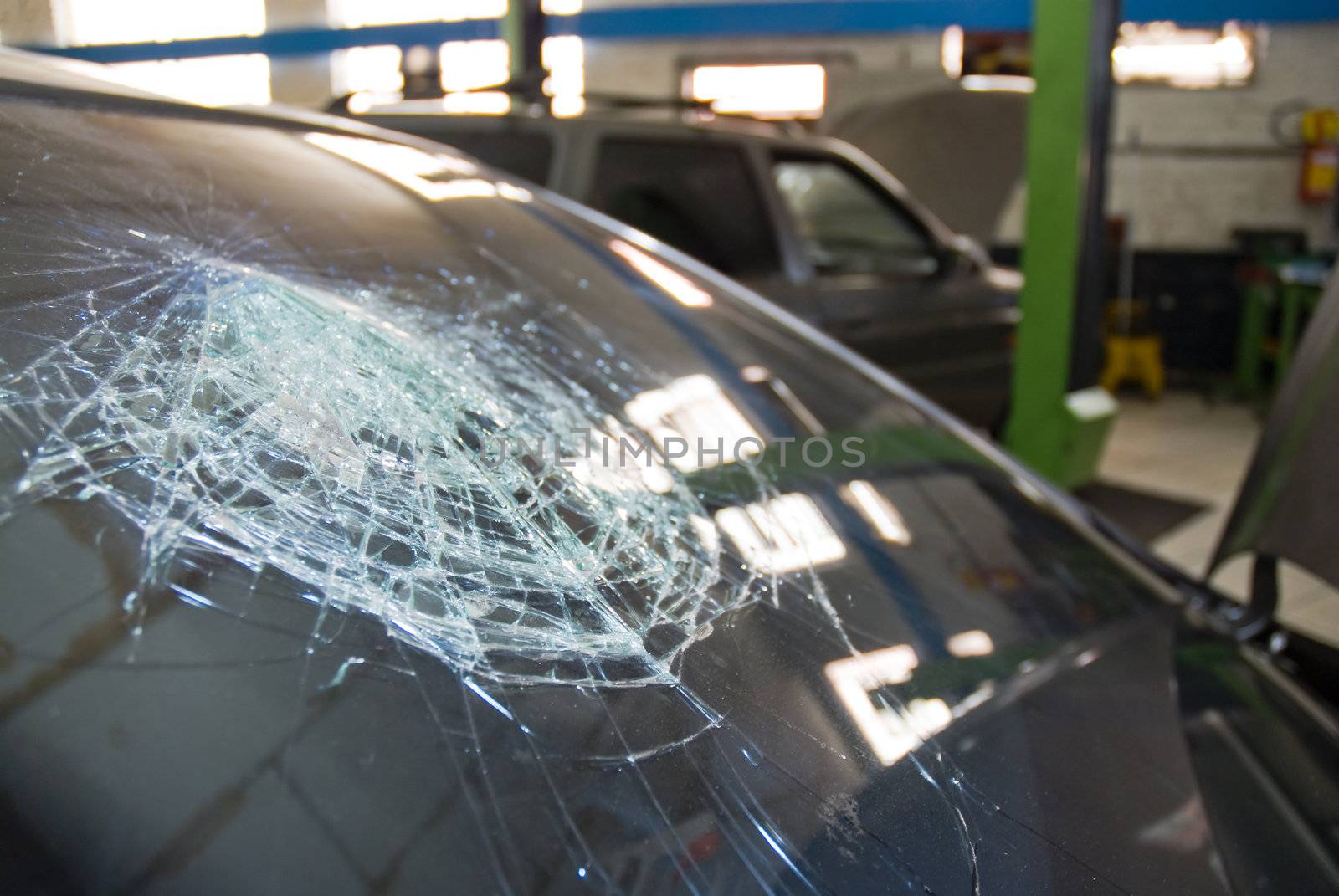 Detail shot of a shattered car windshield in a repair shop.