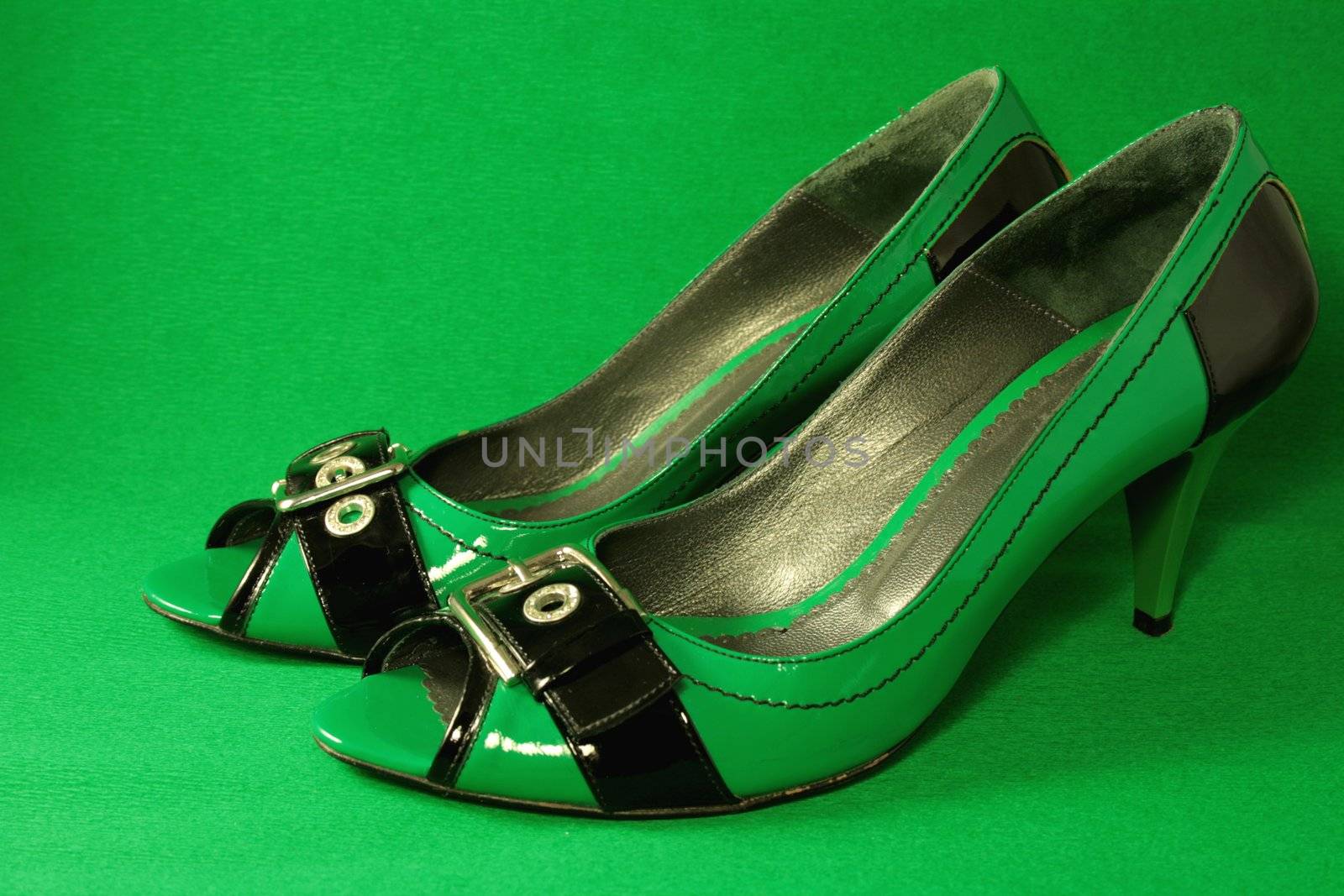 Green High-Heeled Shoes Close-up on green background. Series