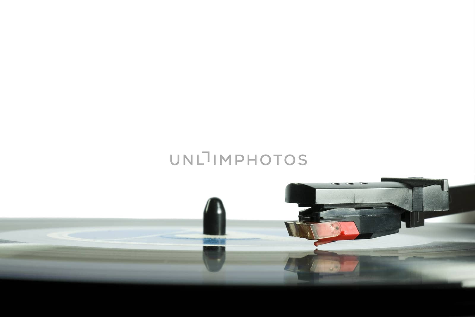 Record player needle close-up, with LP underneath.l