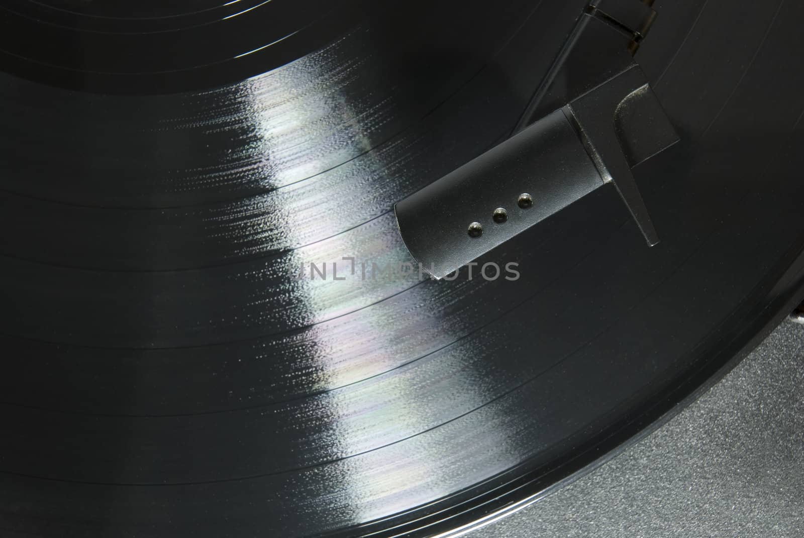 Cropped image shot directly from above of a record player needle, with LP underneath