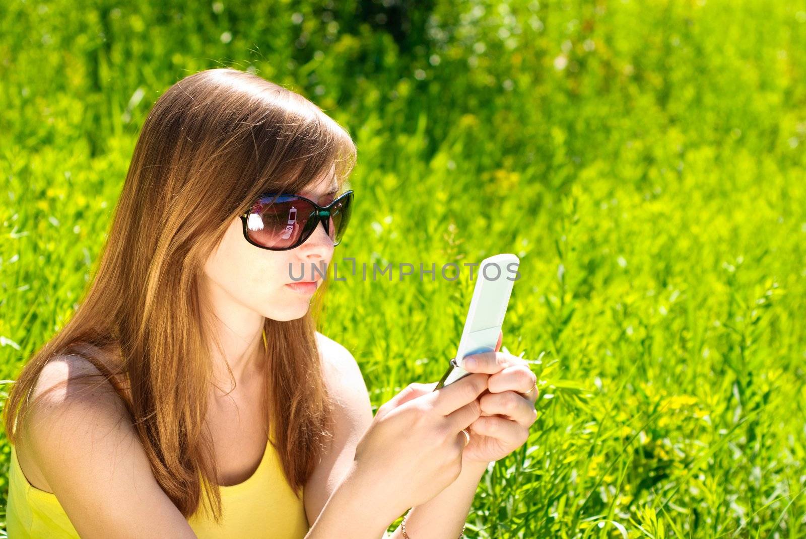 Smiling beautiful woman with mobile phone outdoor. Sunny summer day.