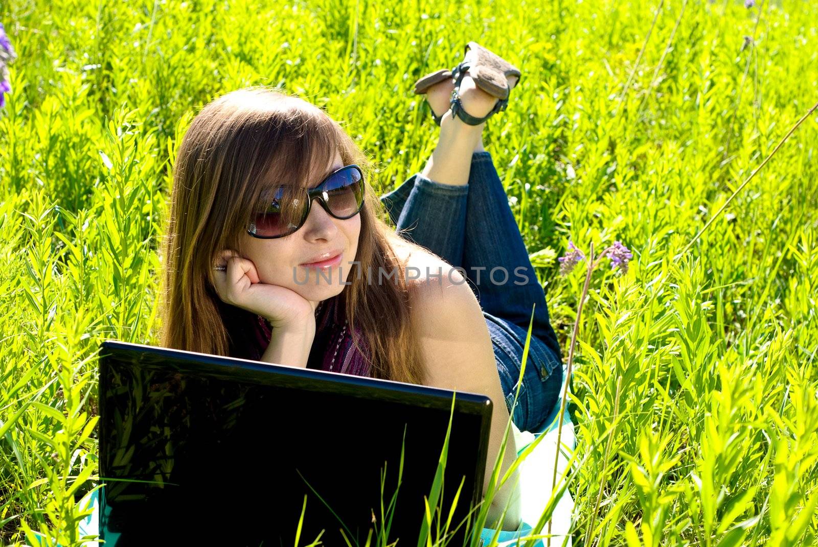 Young beautiful woman with laptop outdoor. Sunny summer day.