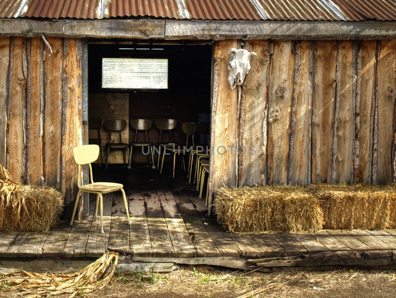 Chairs and straw bails on the porch of a shed in prairie Alberta.