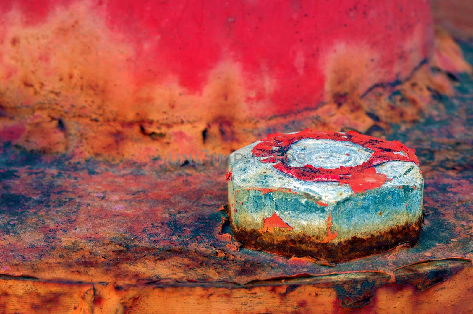 Closeup picture of a bolt on a highly textured and weathered metallic surface