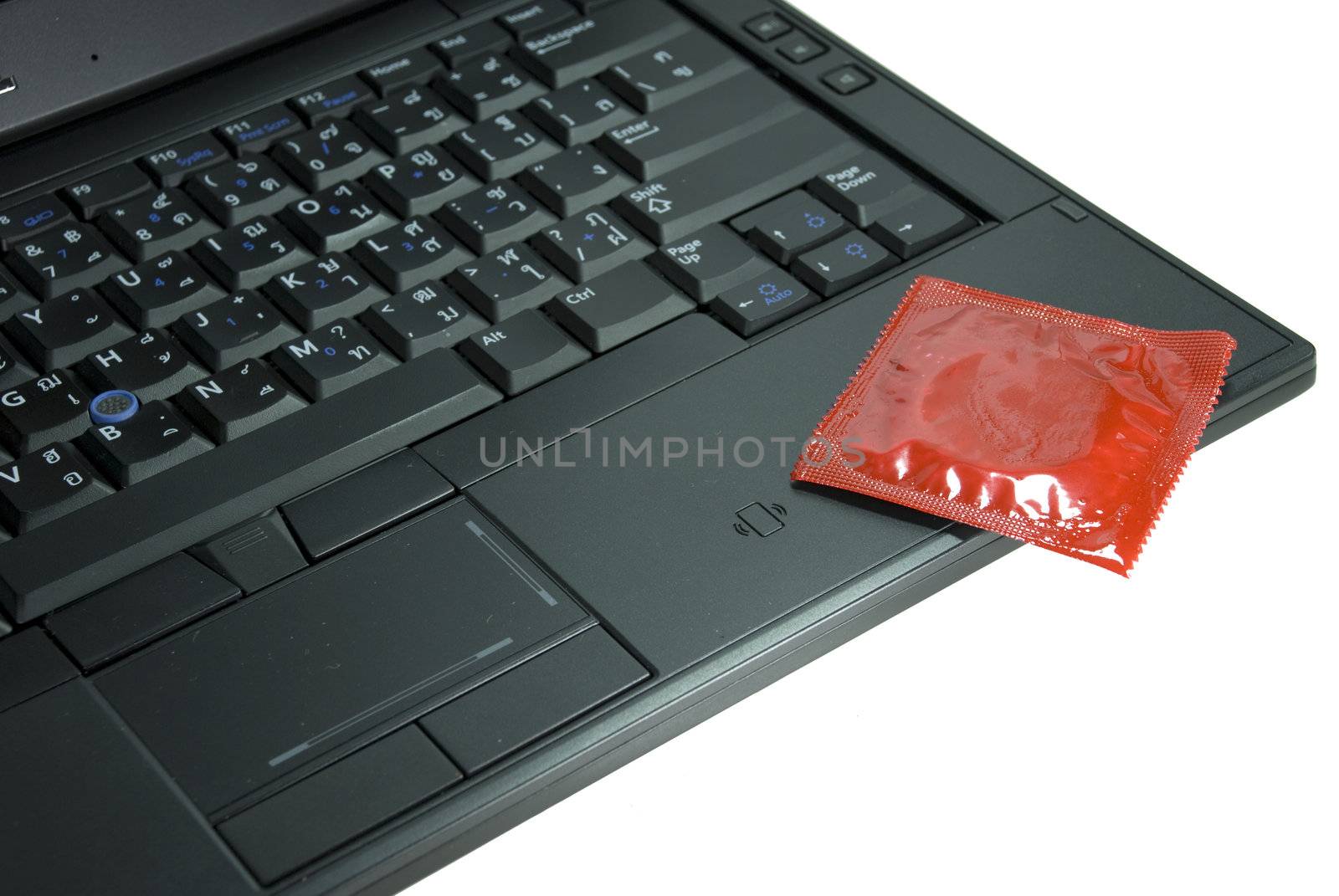 A red condom sitting on a laptop, encouage sexual intention at office