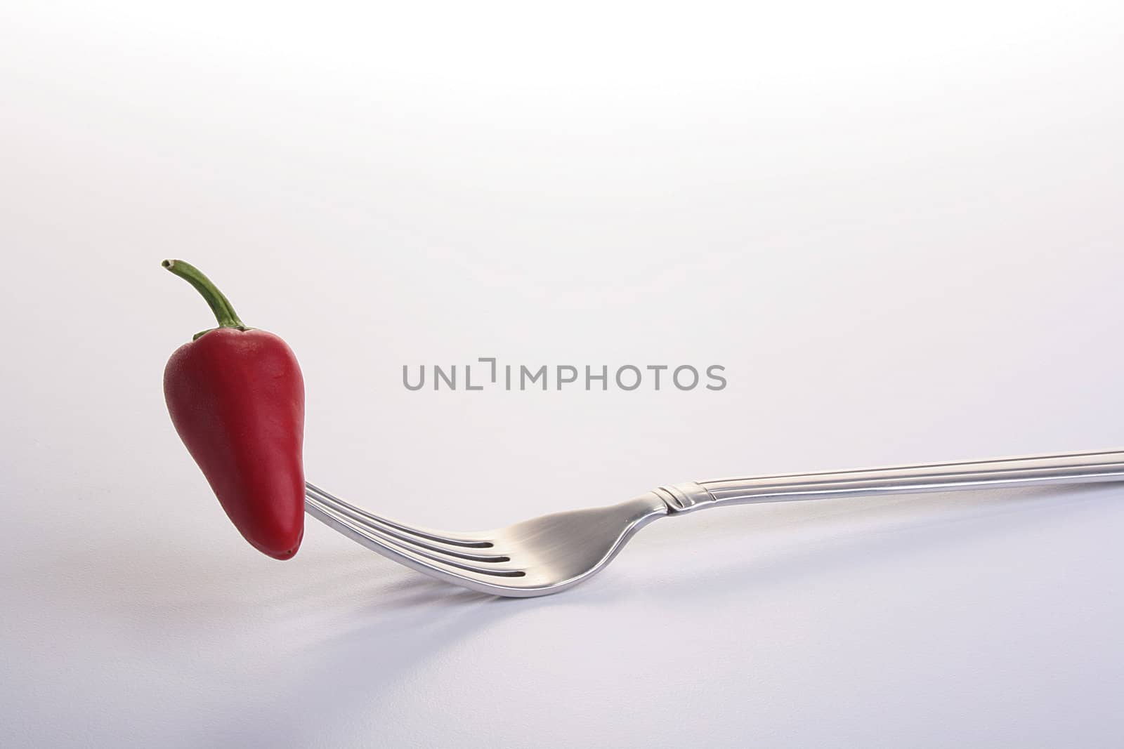The red hot pepper is pinned on a fork.