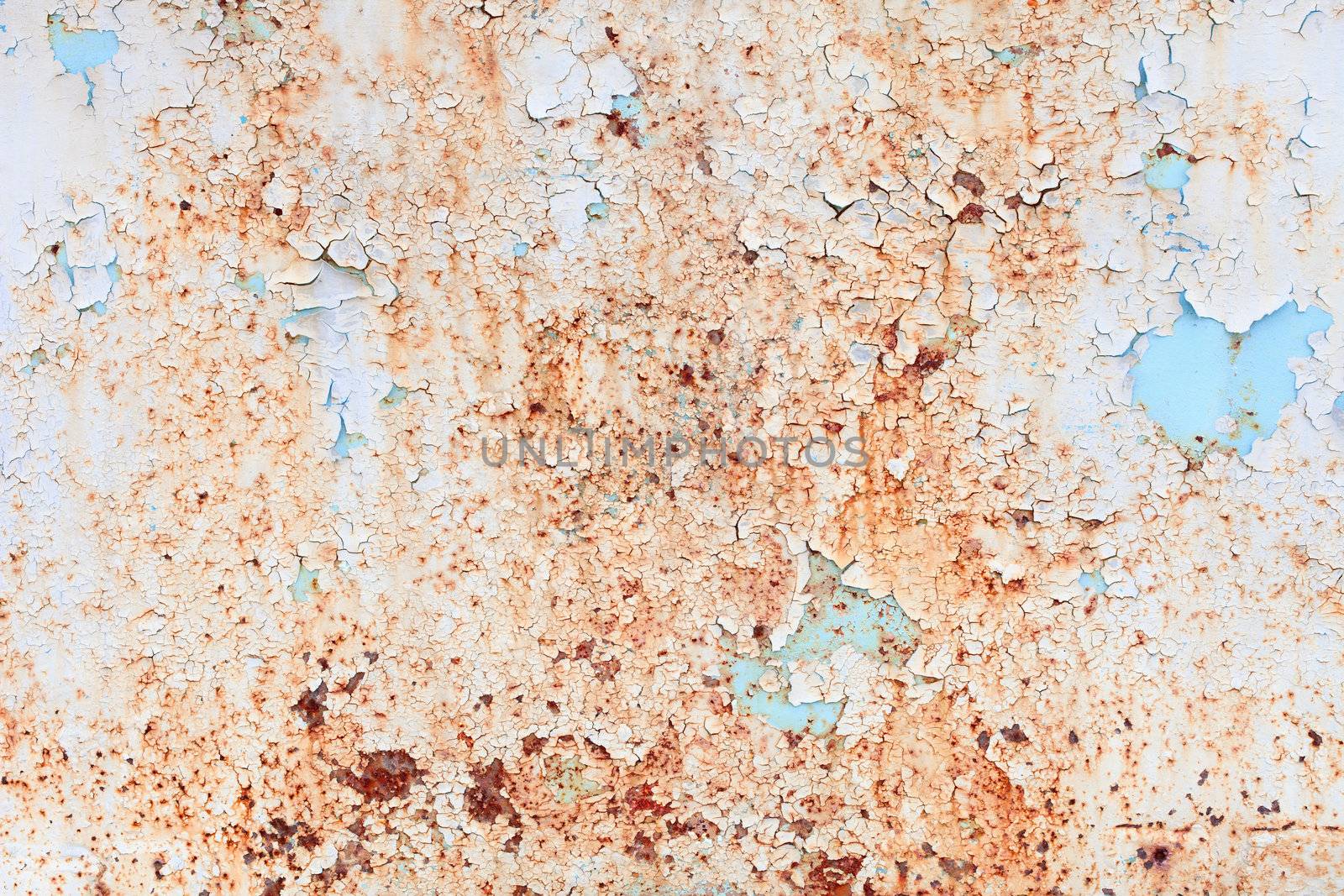The rusty weathered surface of a steel sheet with paint scraps