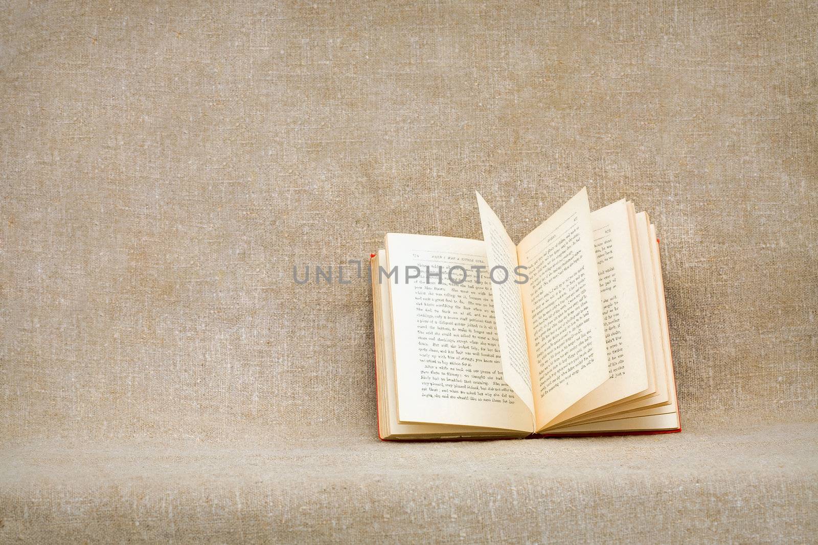 The open old book against a rough brown canvas