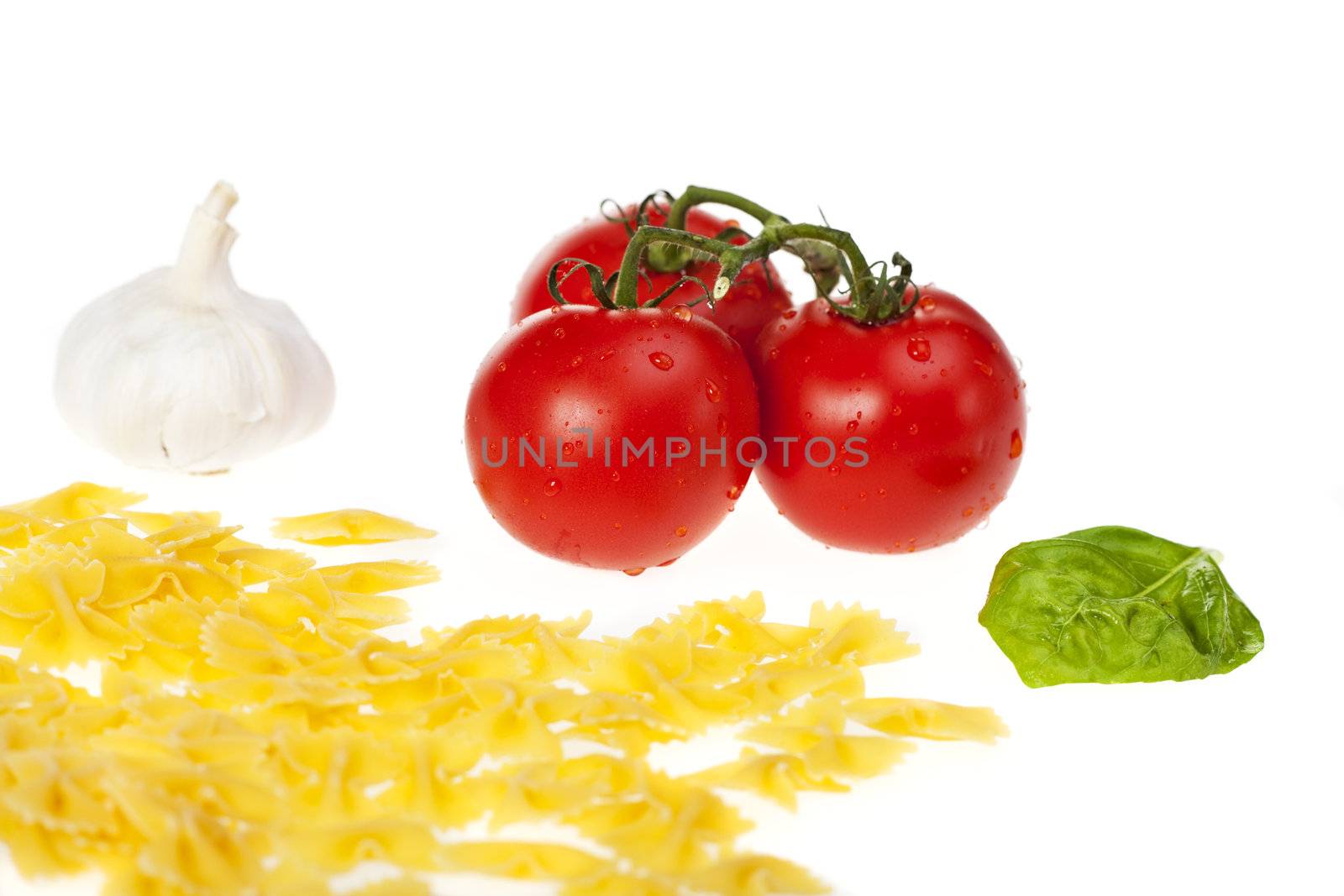 farfalle pasta, tomatoes, garlic and a basil leaf