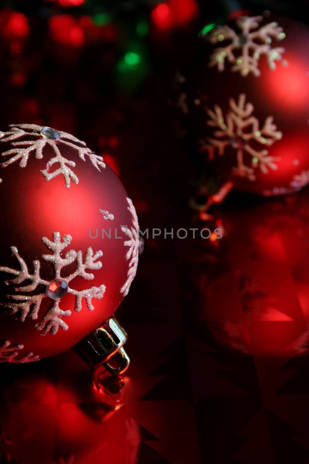 Two red christmas baubles illuminated on glossy red paper.
