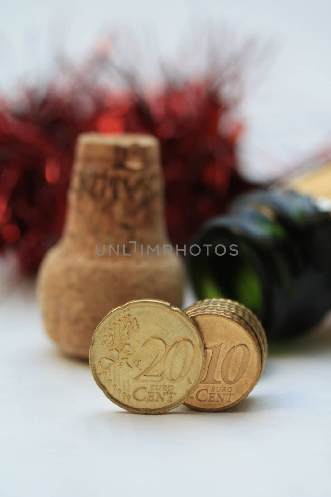 Two euro coins in front of an open champagne bottle and cork