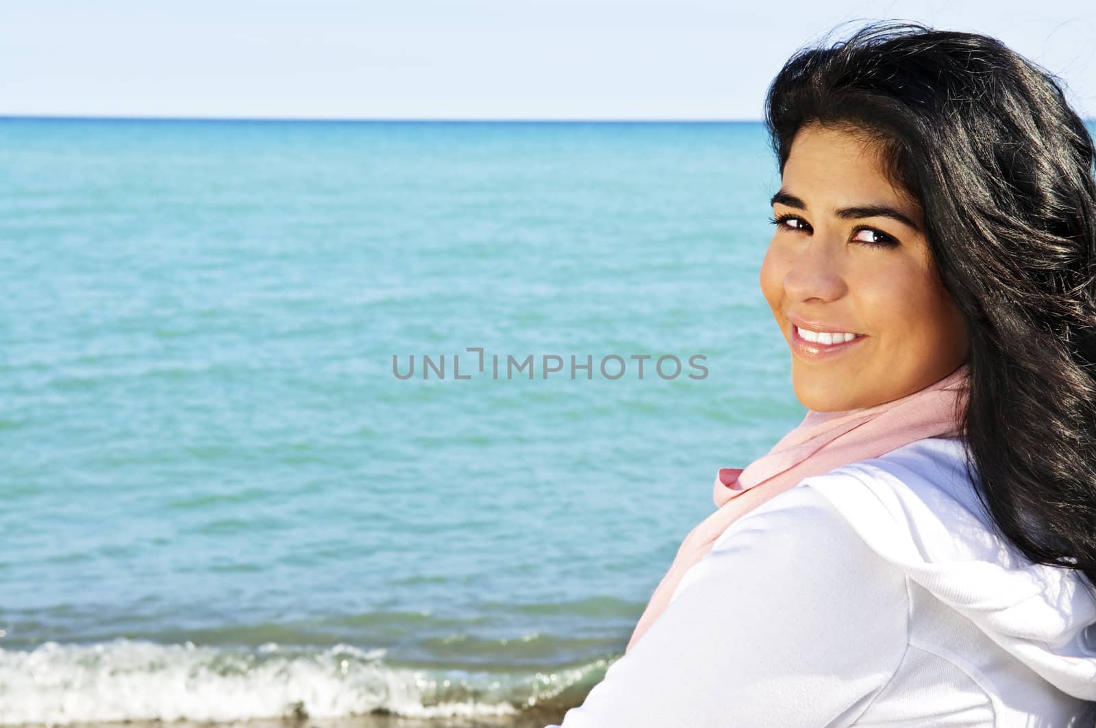 Portrait of beautiful smiling brunette girl at beach looking over her shoulder