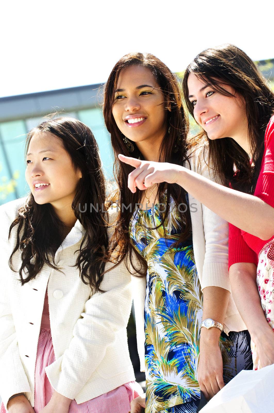 Three young girlfriends at outdoor mall pointing