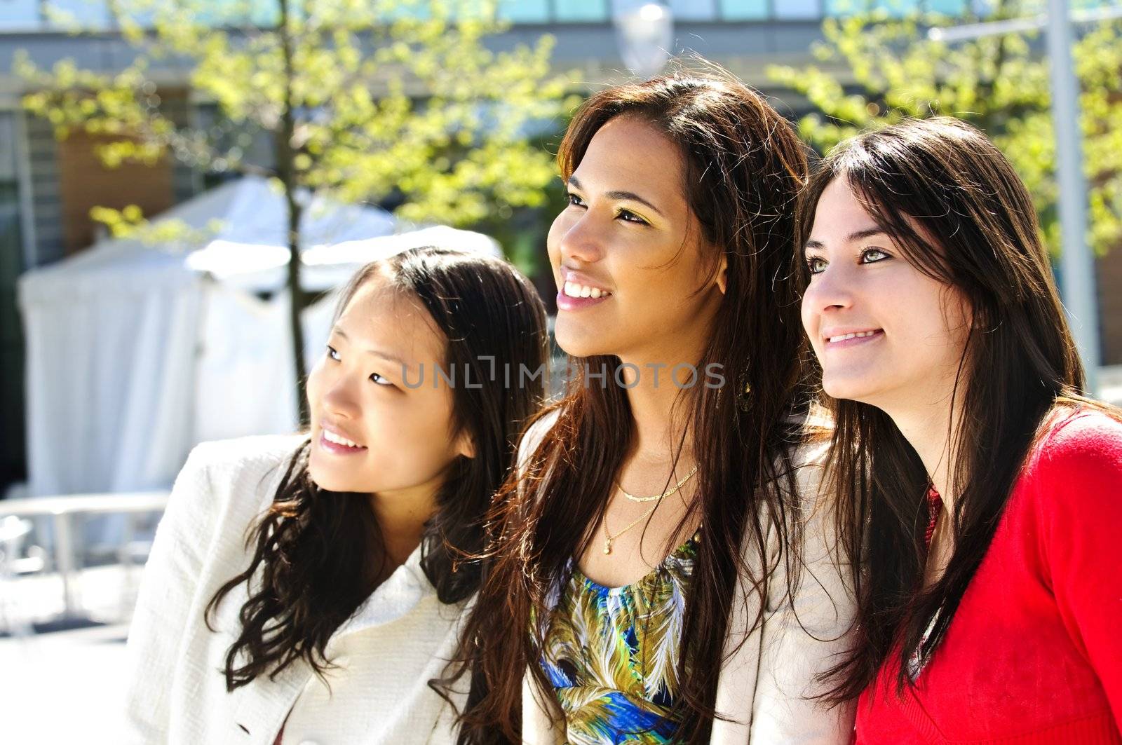 Three diverse young girlfriends smiling into camera