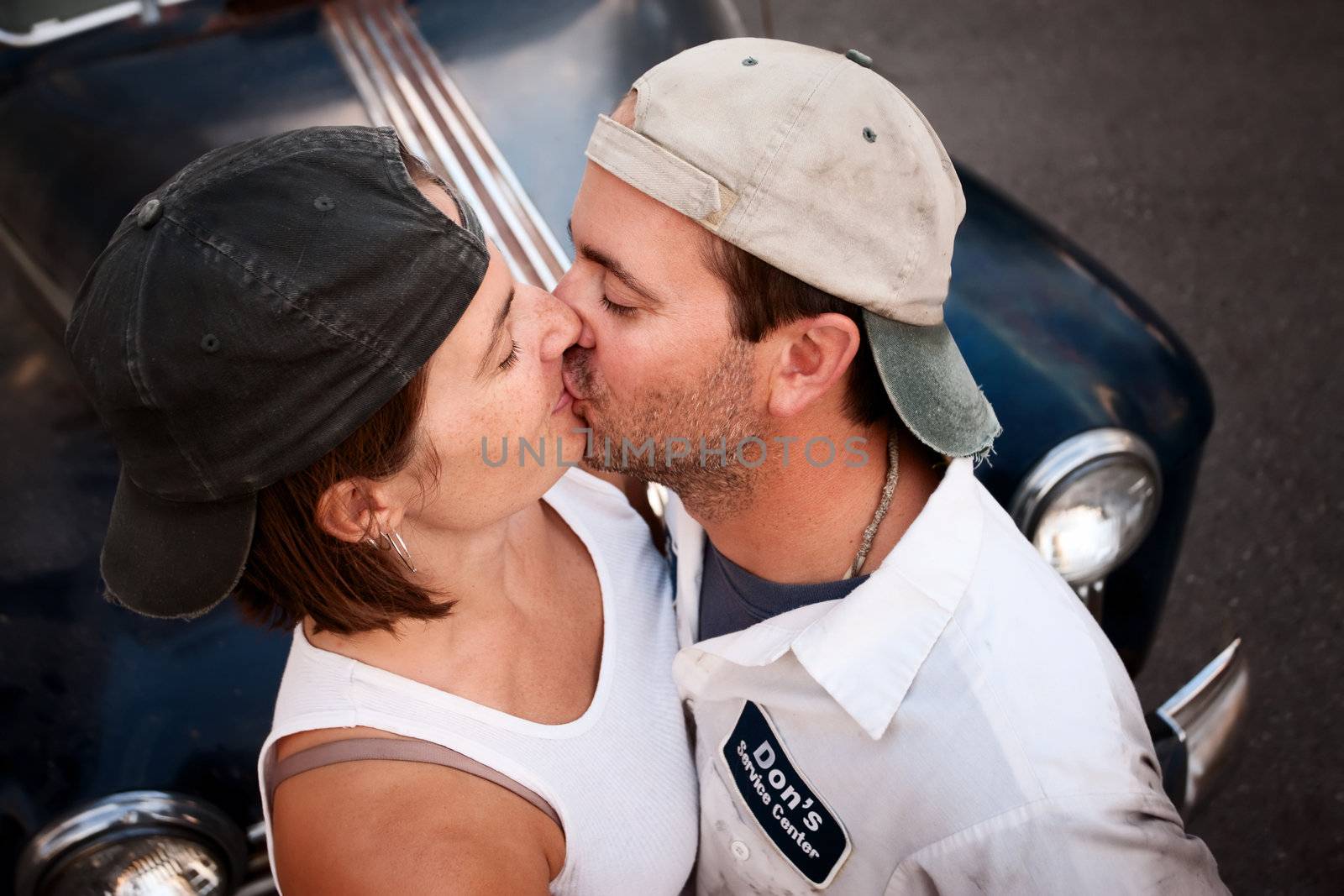 Couple posing with vintage sedan and kissing