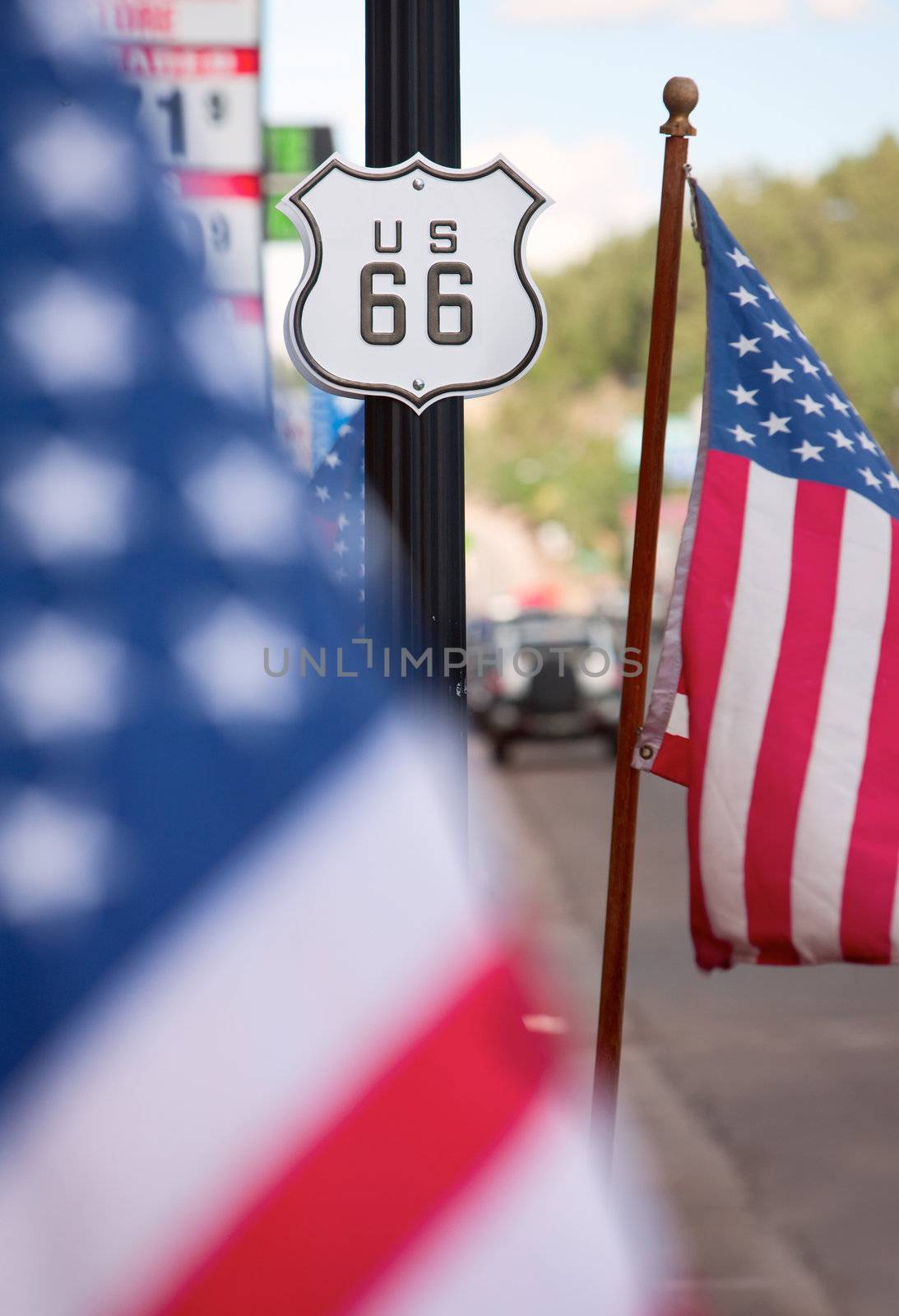 Route 66 sign on side of road with American flags