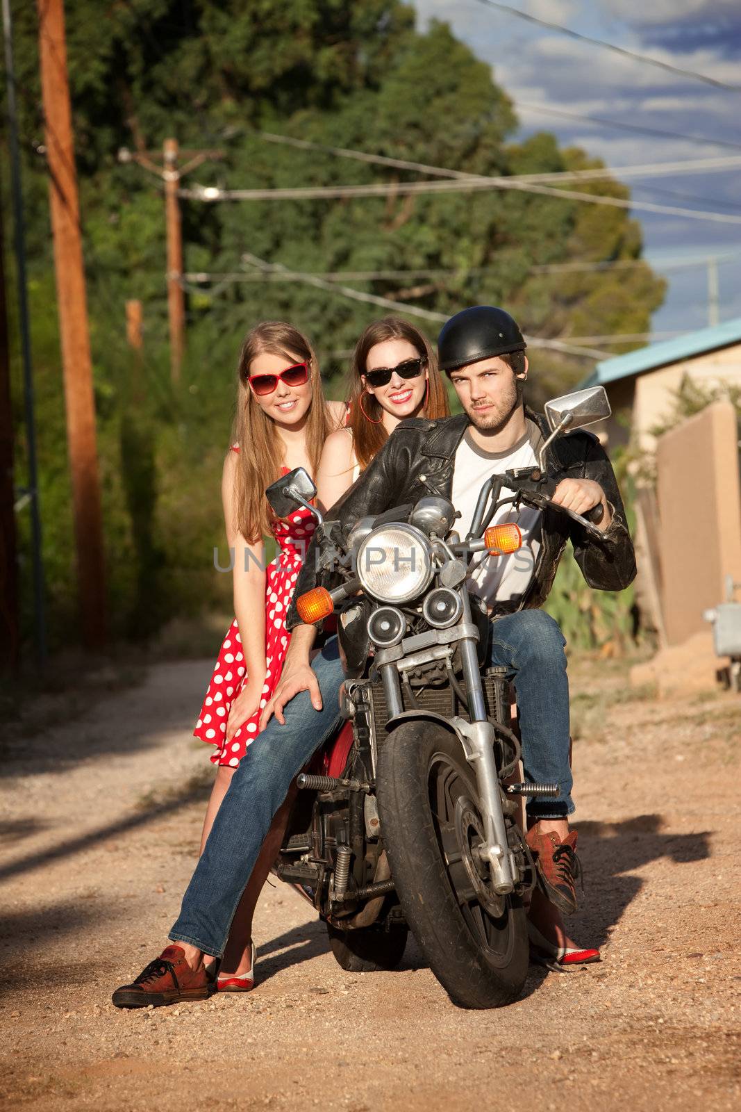 Three young adults posing on vintage motorcycle