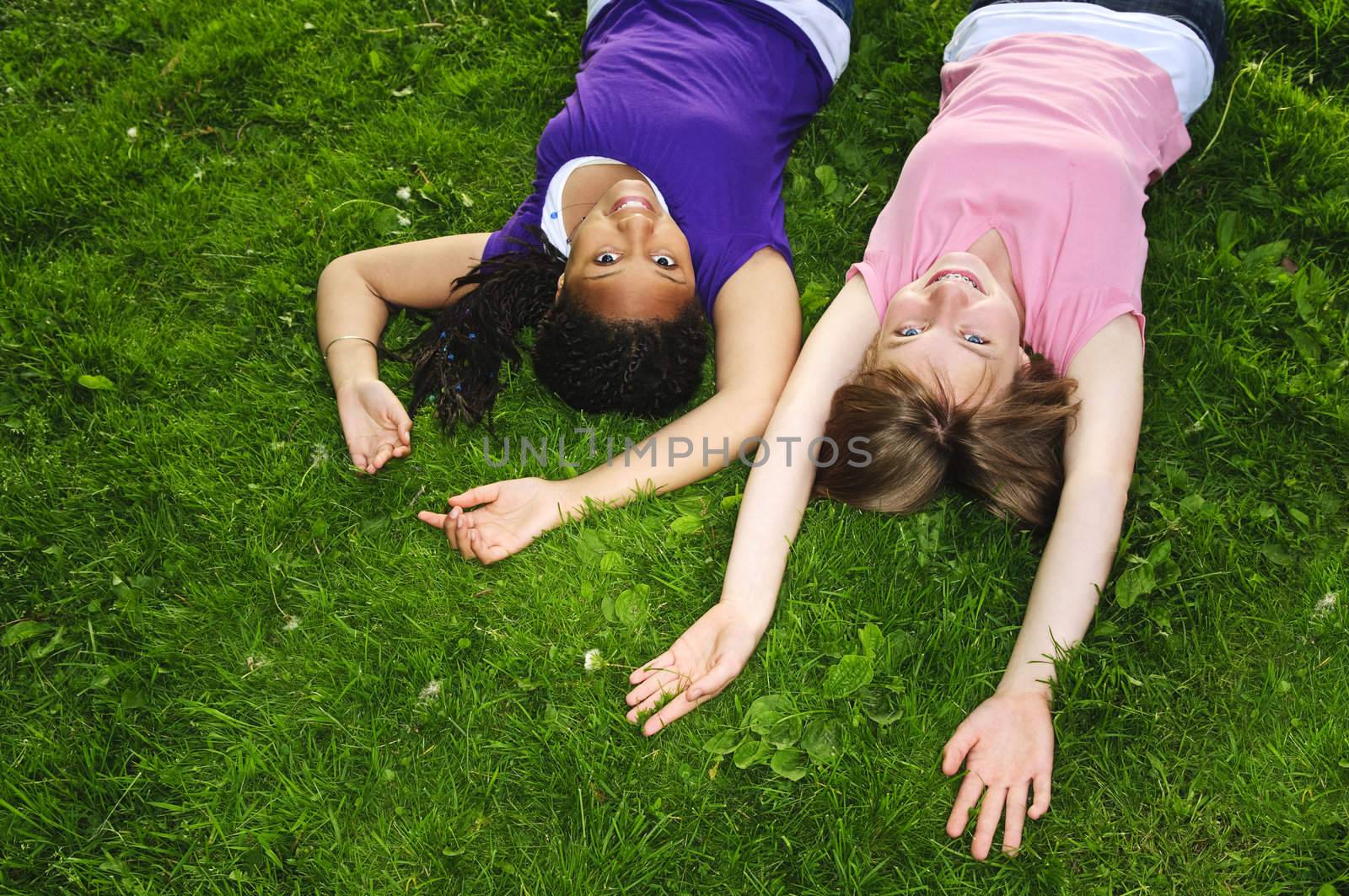 Two teenage girls laying on grass arms outstretched