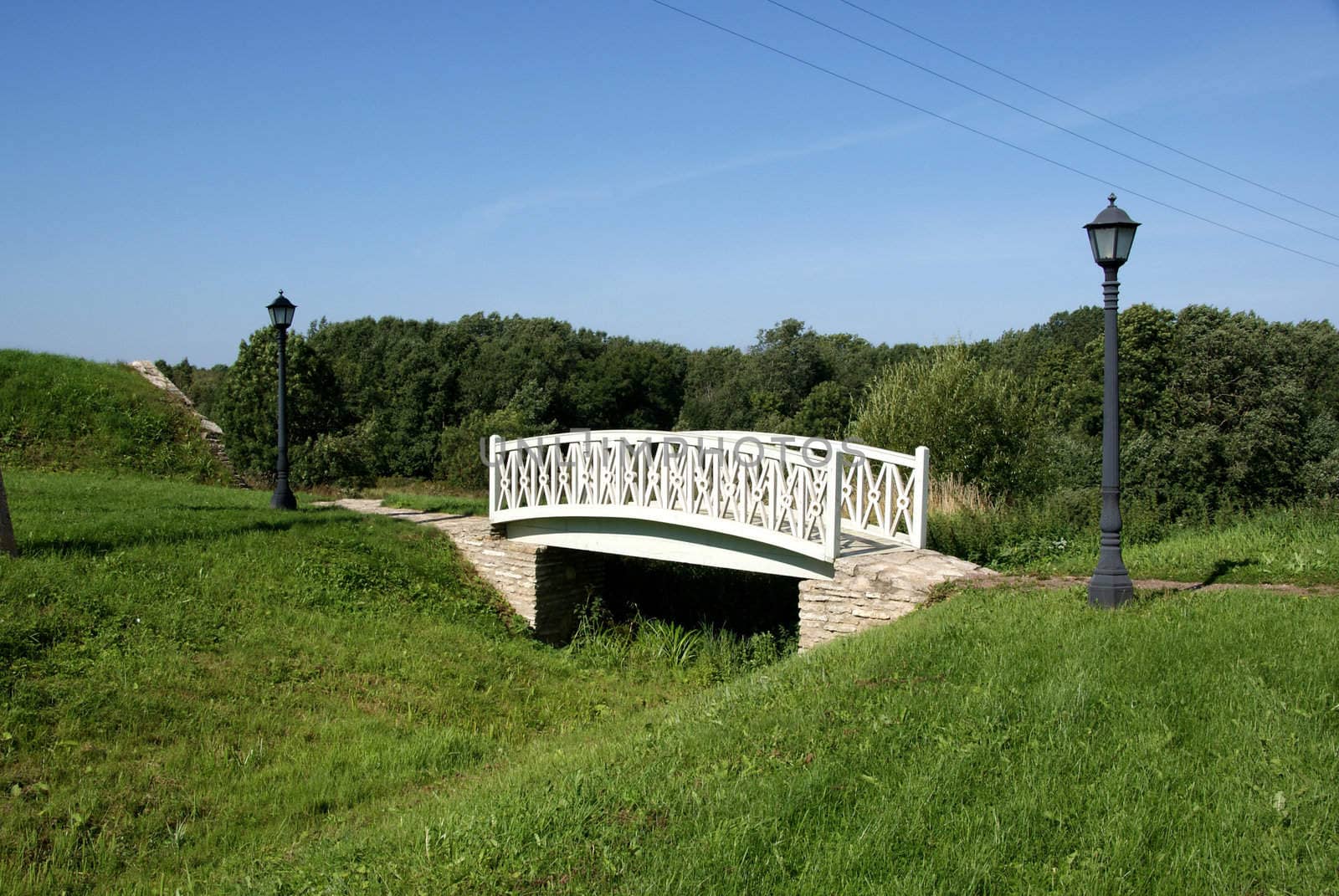 The white bridge on a background of a green grass and the sky