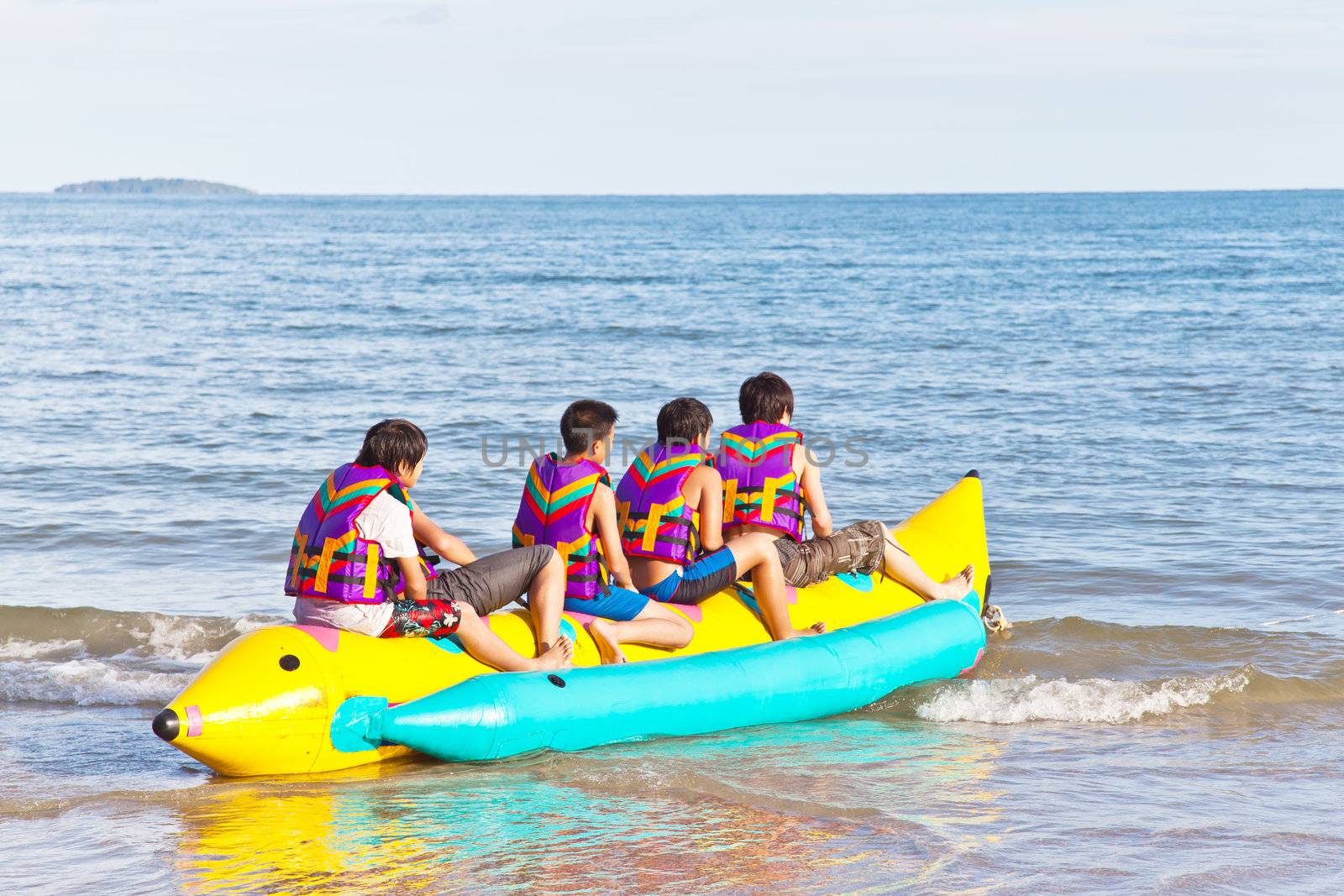 group of young people riding banana boat  by FrameAngel