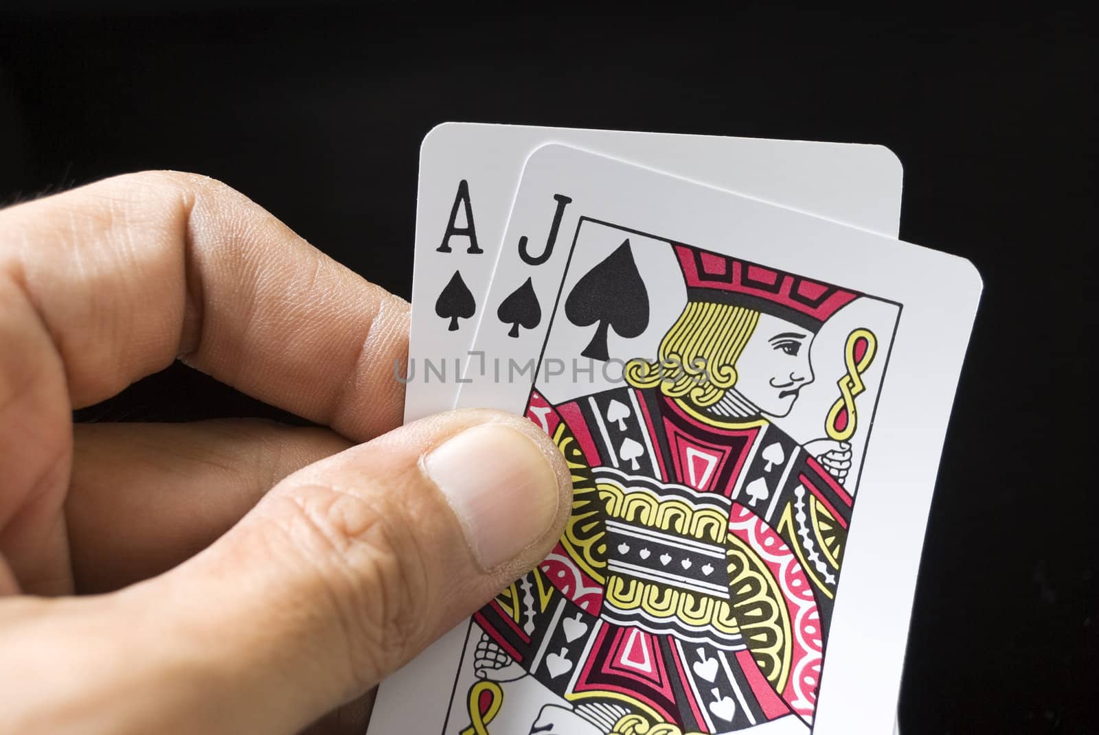 Blackjack cards held by hand against black background