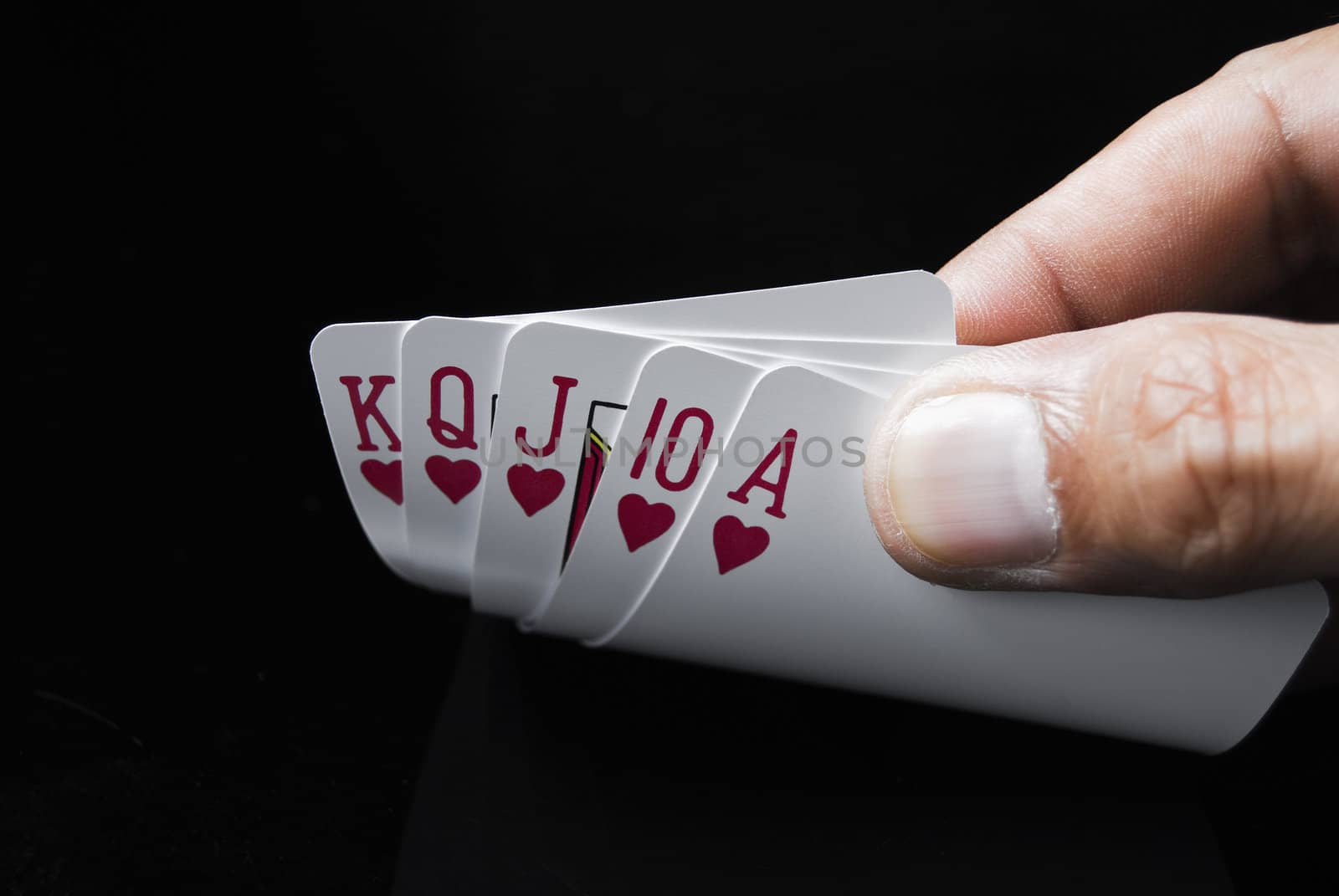 Royal Flush held by hand against black background