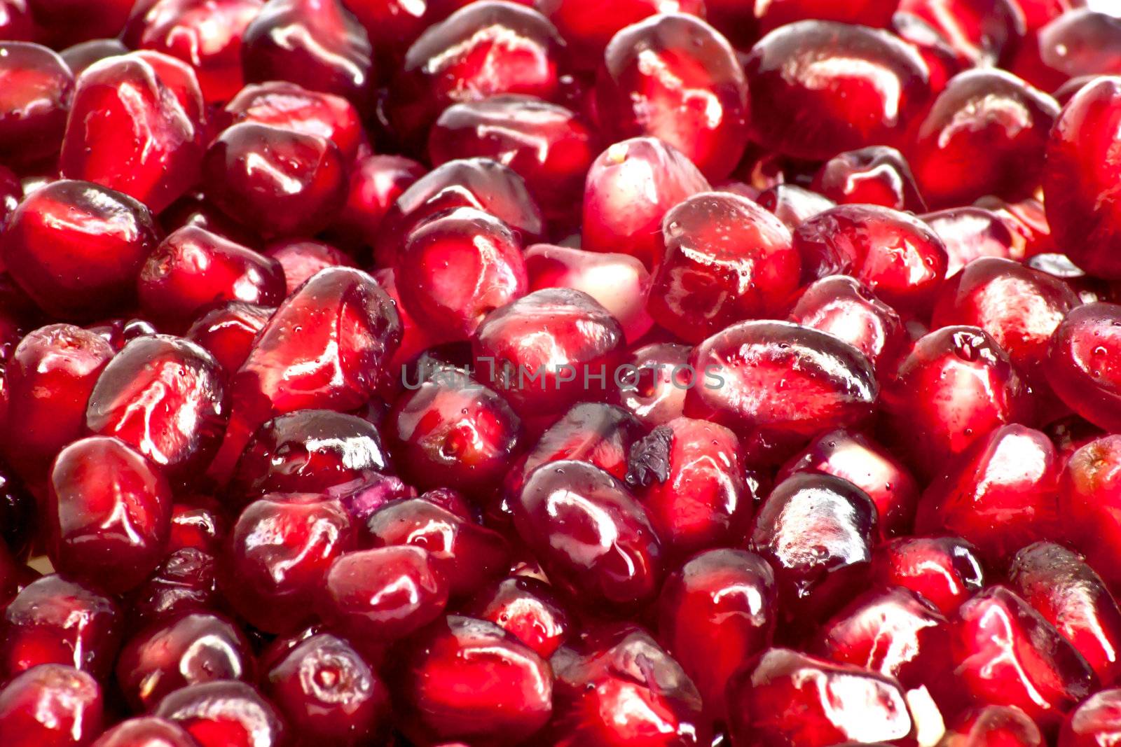 Extreme close up background of a red juicy ripe pomegranate fruit seeds 