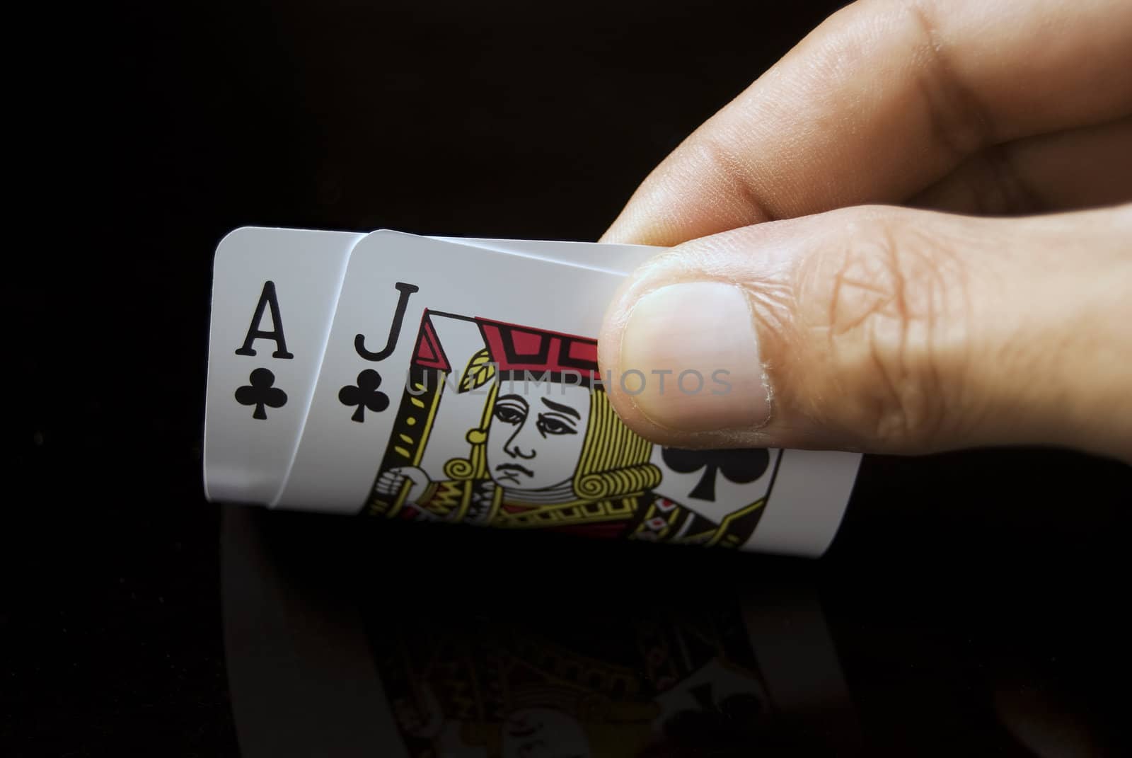 Blackjack cards held by hand against black background