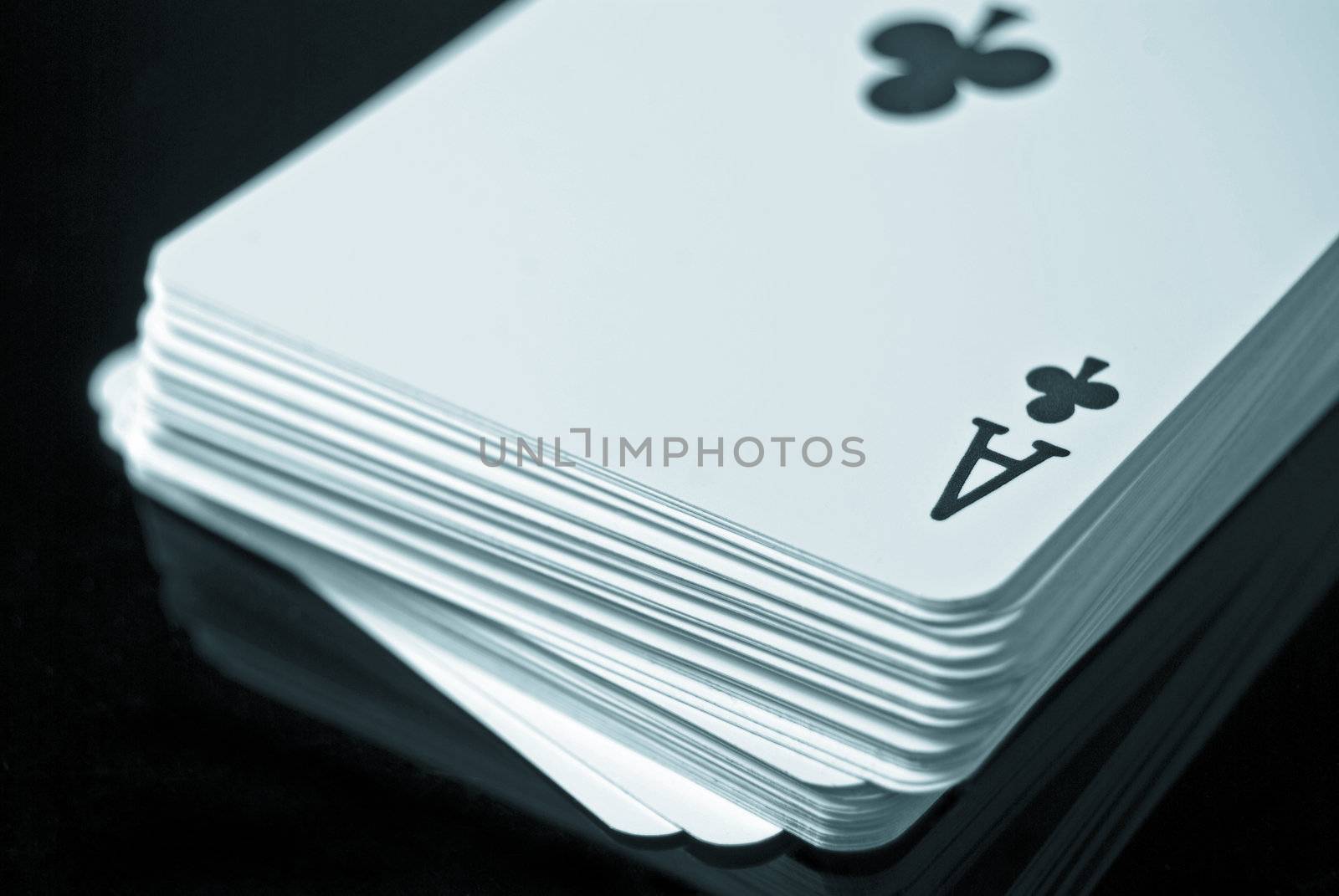 Deck of cards against black background; Ace of Clubs on top