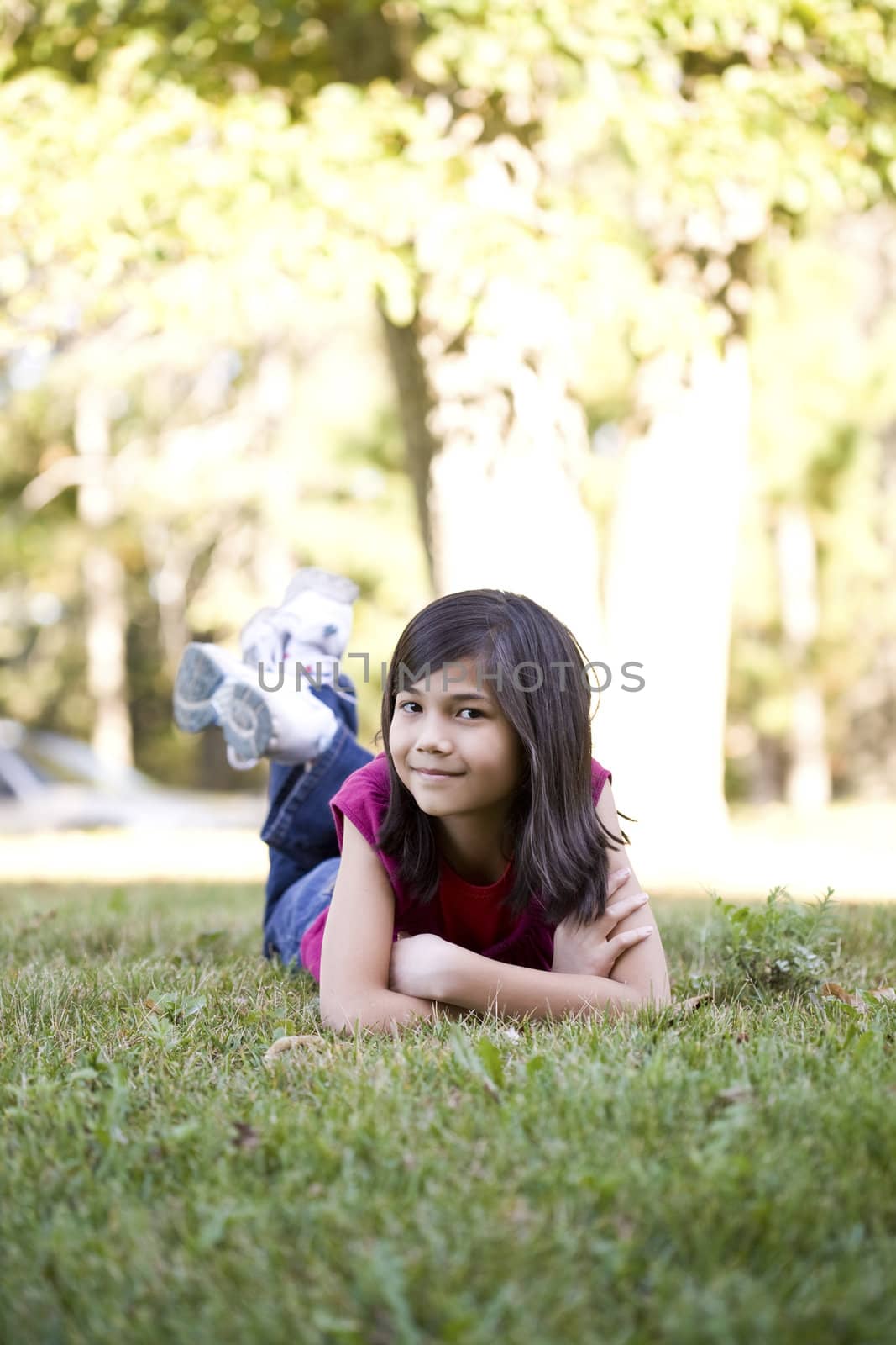 Ten year old girl lying down on grass, chin in hand