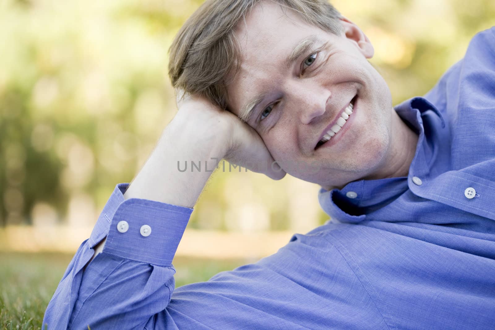 Handsome businessman relaxing on grass in summer