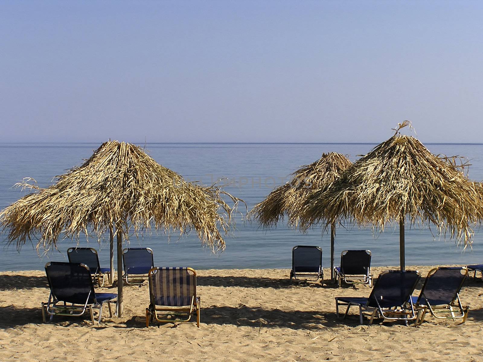 Sunshades and sunbeds at sandy greek beach.