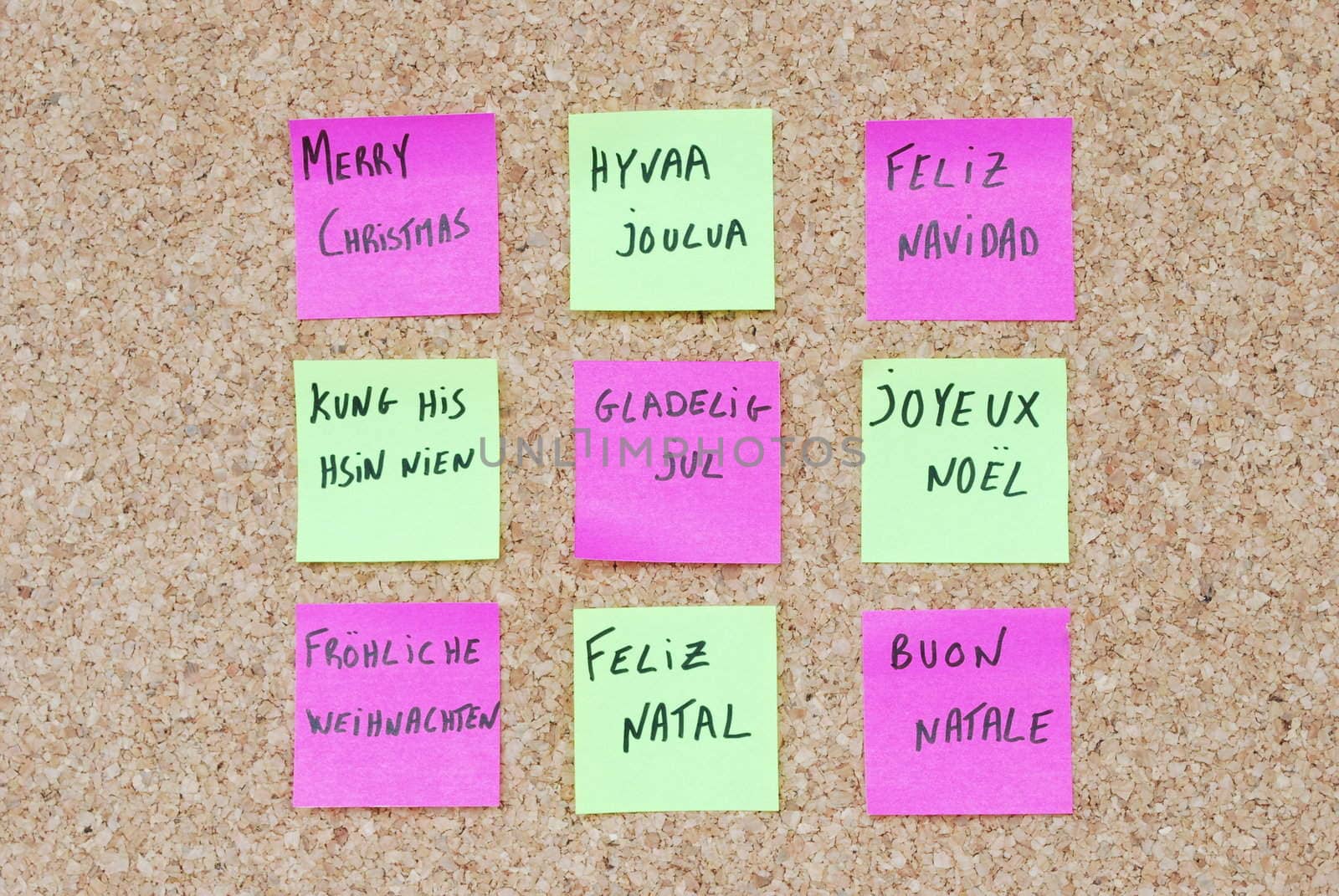 Merry Chritmas tree concept in nine languages with colorful post-it notes on a corkboard