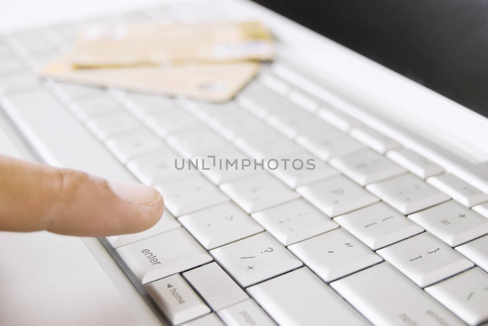 Finger of adult on computer keyboard and credit cards at background