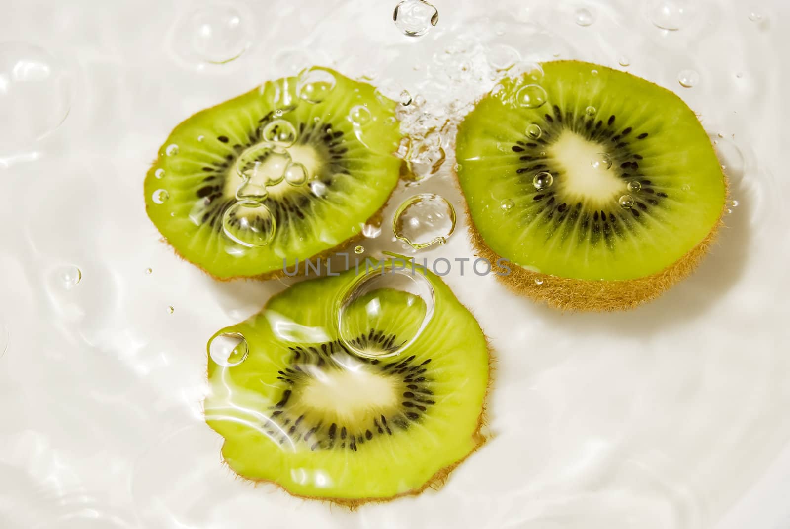Three slices of kiwi fruit in water