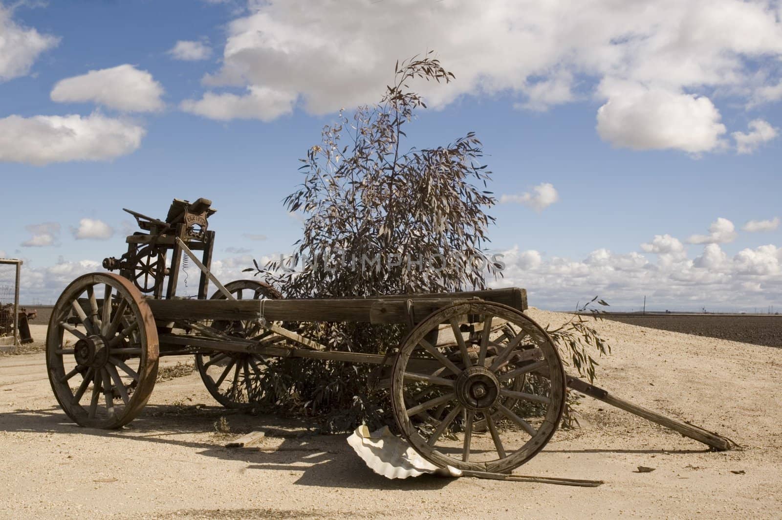 Old agricultural wagon on a farm in California with cumulus clouds in background