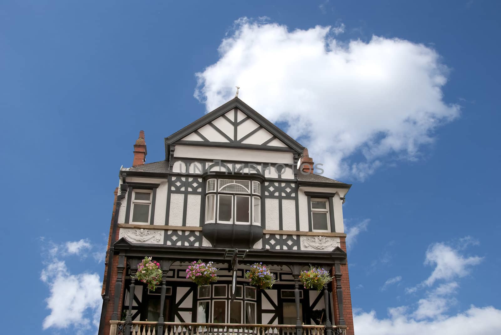 A Half Timbered English Pub with Flower Baskets against a Blue Sky