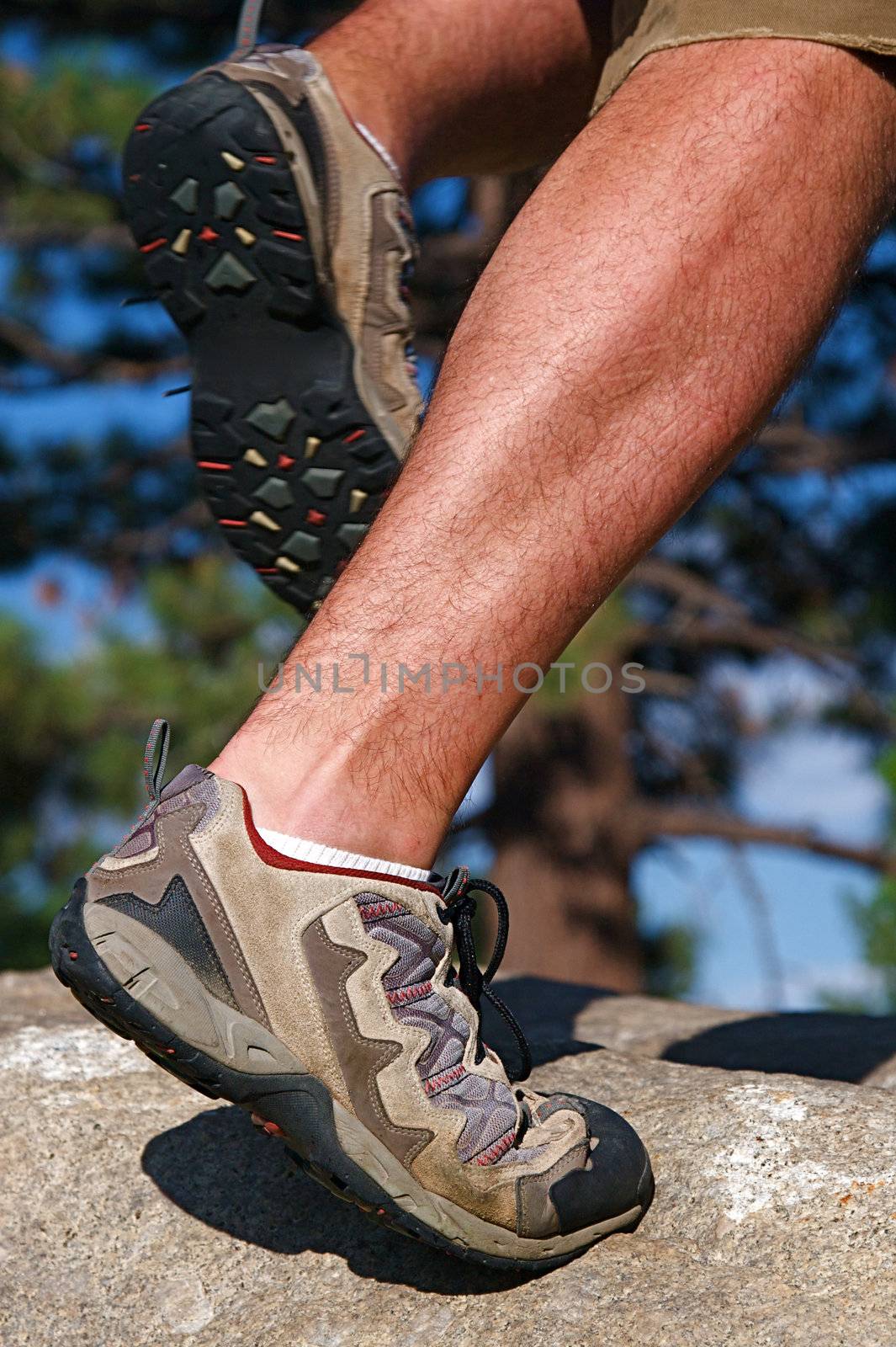 Trail runner climbing a steep rock in his path