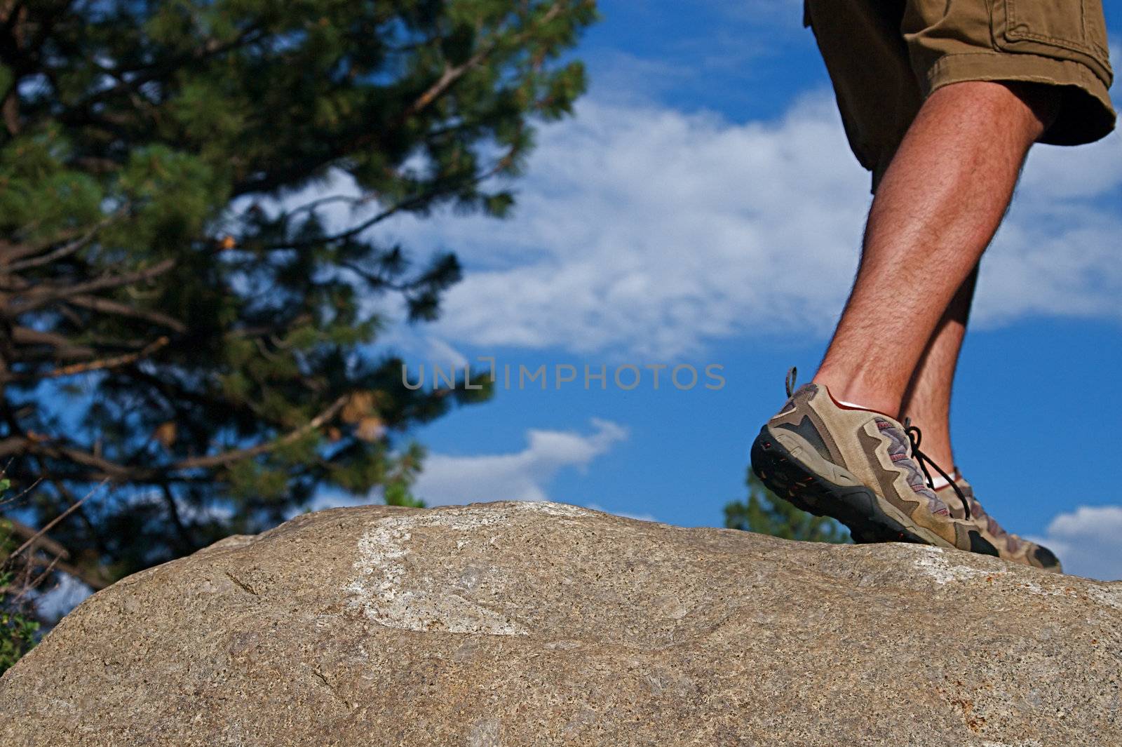 Trail runner climbing a steep rock in his path