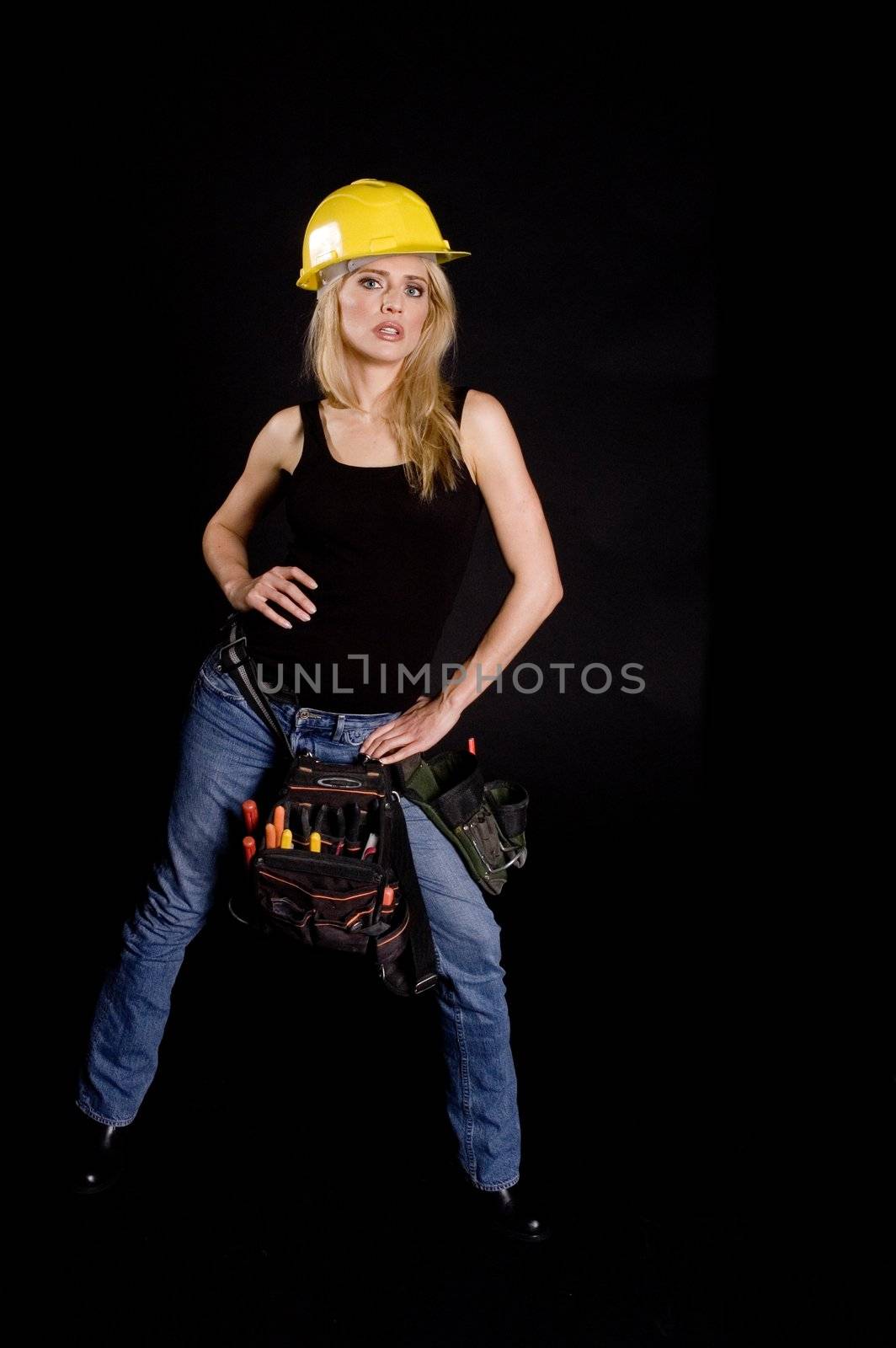 sexy blond female construction worker with hard hat and tool pouch on black background