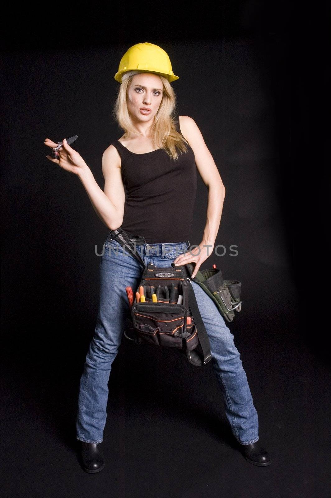 sexy blond female construction worker with hard hat and tool pouch on black background