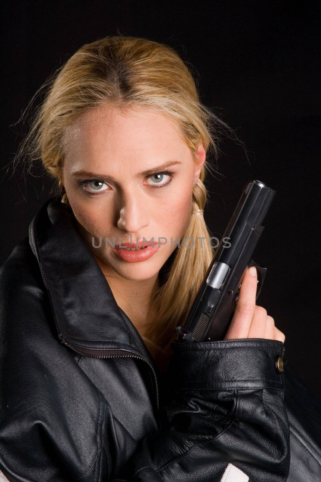 Sexy blond woman with gun in leather jacket on a black background